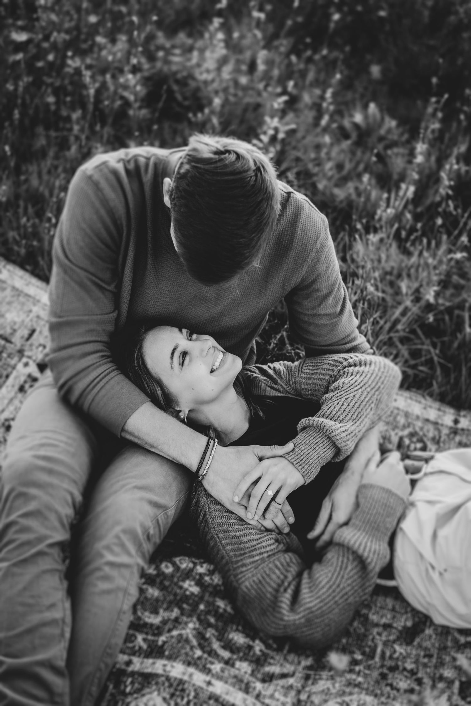 Intimate black and white photos of couple lying in grass field.
