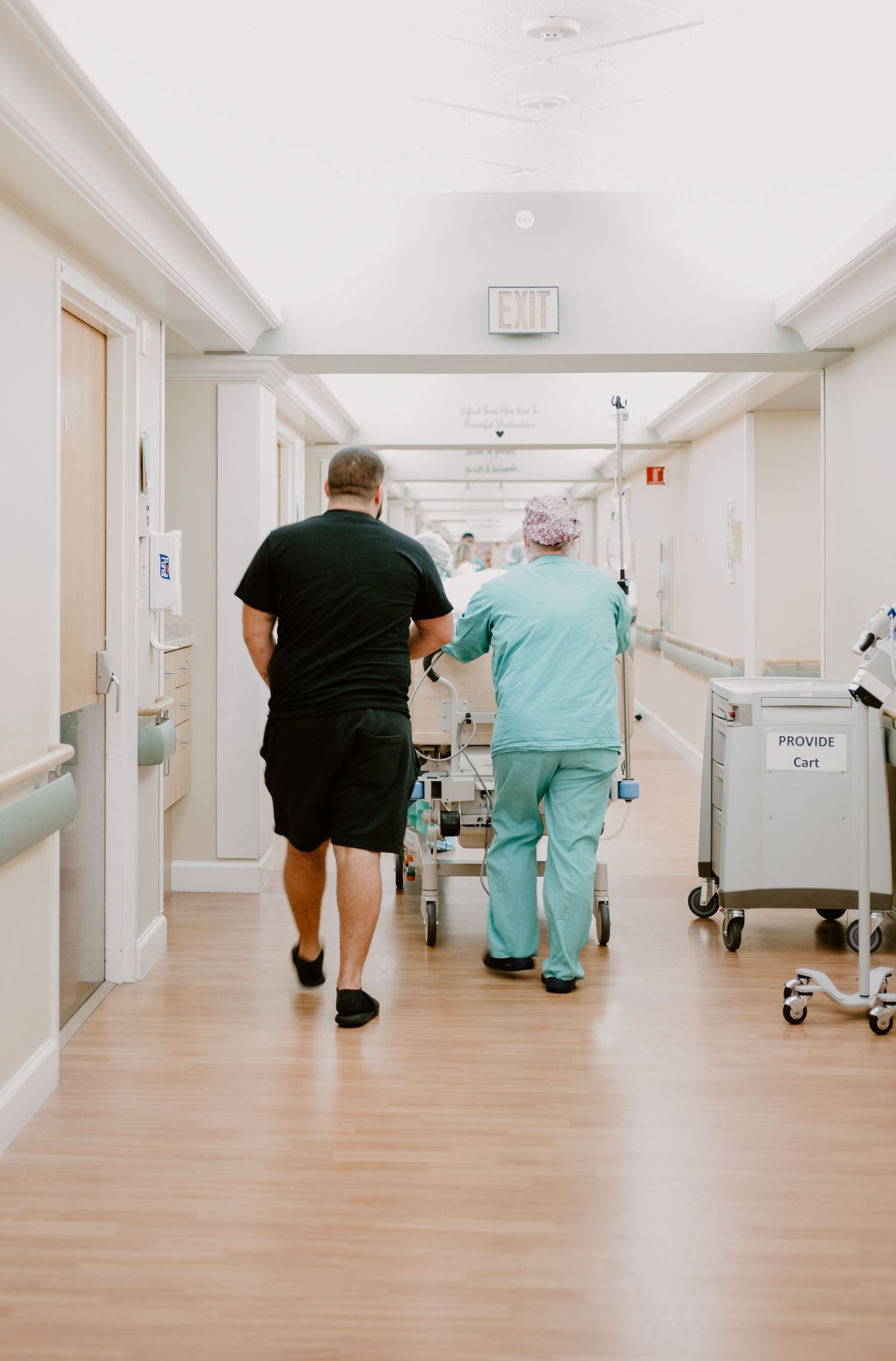 Medical staff walking patient down hospital corridor.