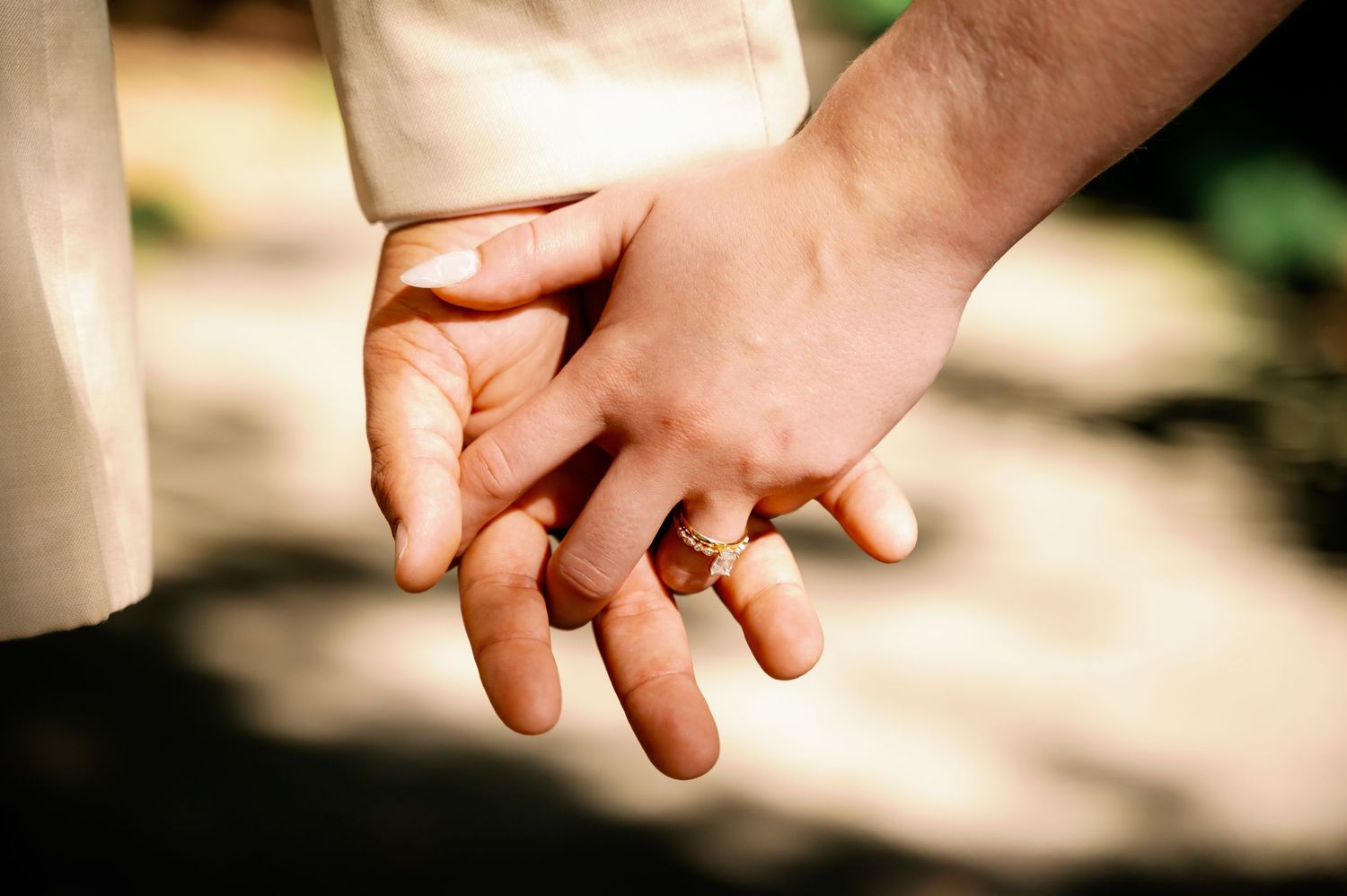 Close-up of wedding rings and joined hands showing intimate connection.