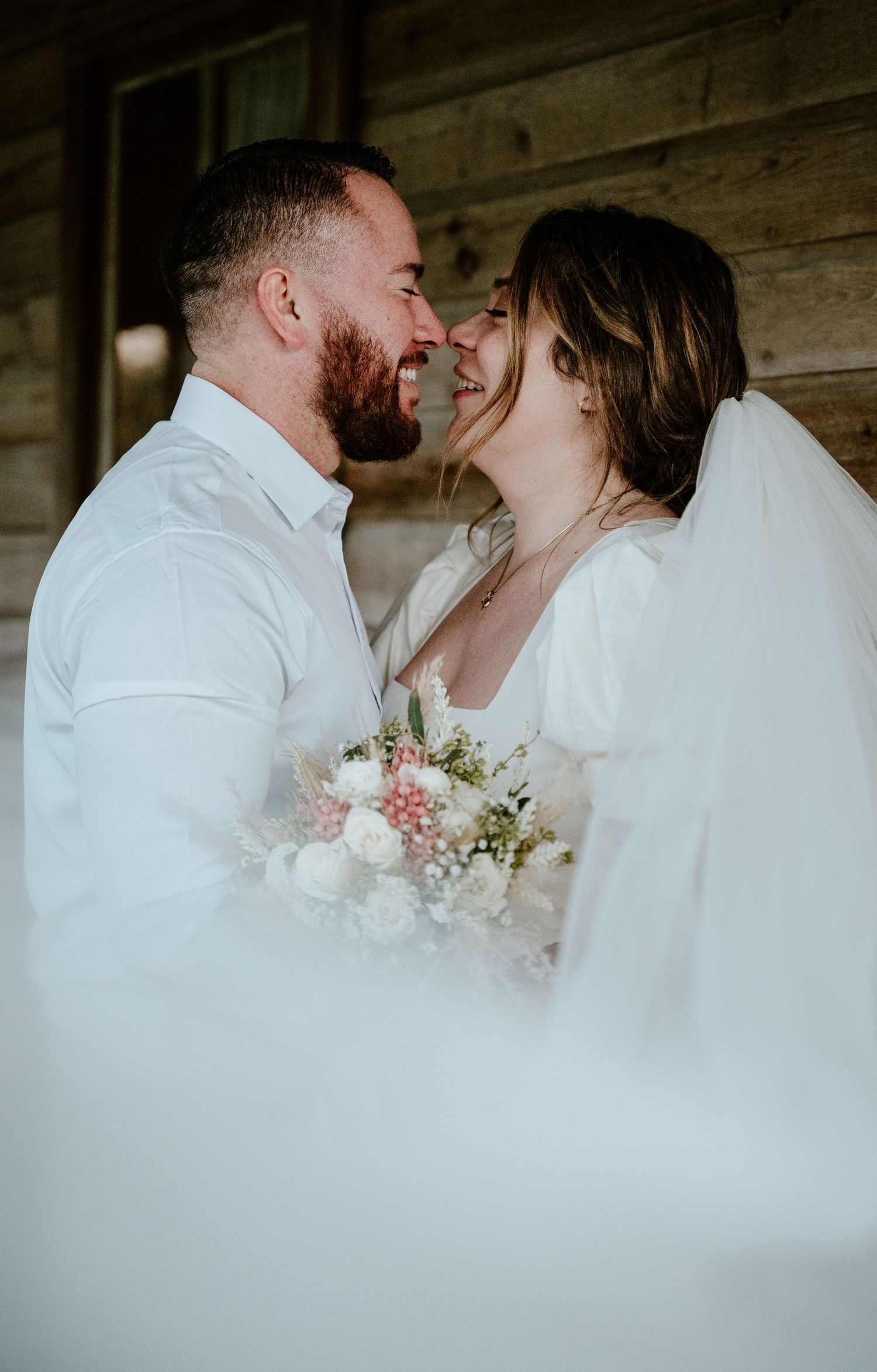 Dreamy wedding portrait with soft white veil and delicate pink bouquet.