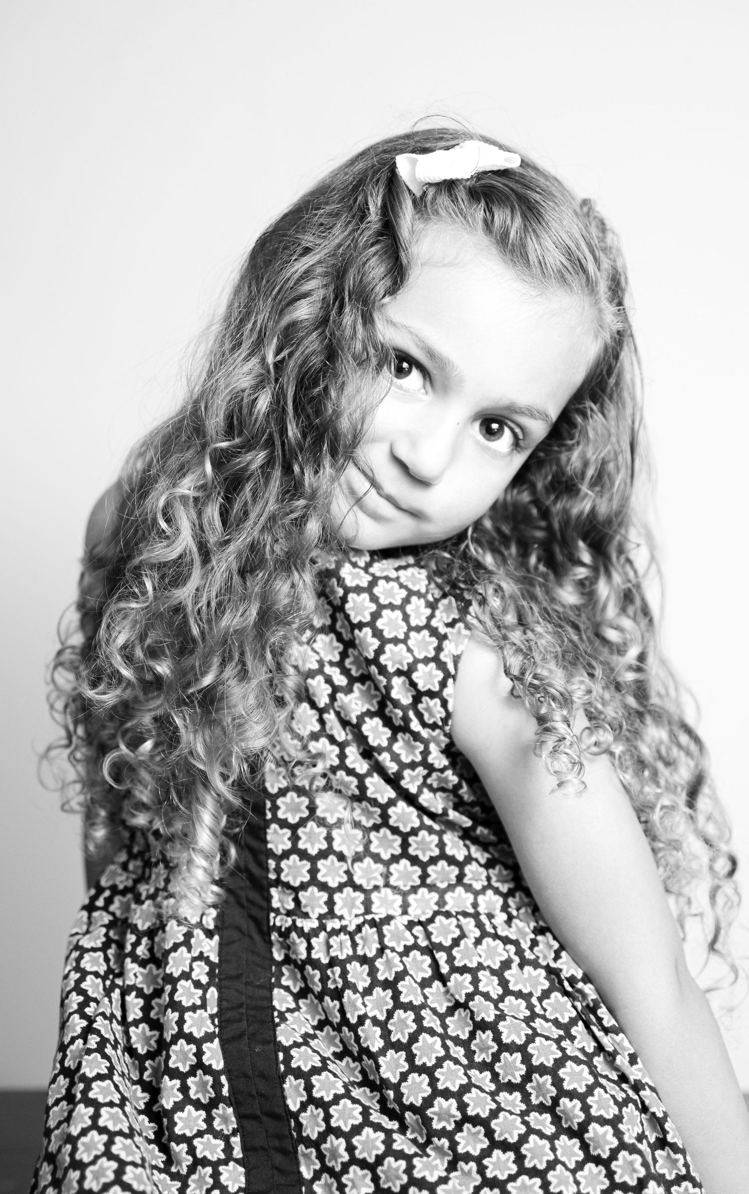 Black and white portrait series showing playful expressions and curly hair in floral print dress.