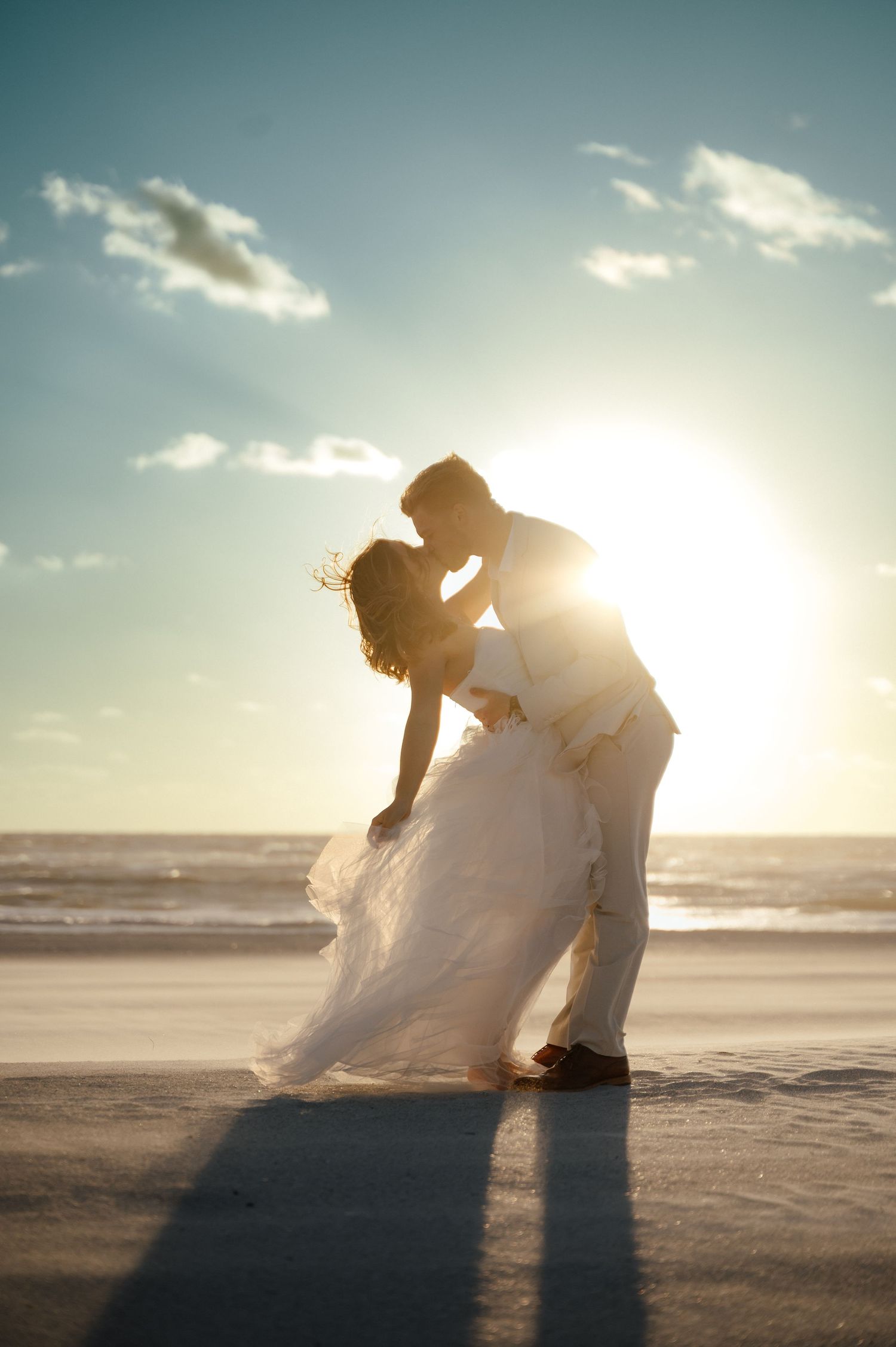 Romantic silhouettes of couple dancing on beach at sunset with dramatic lighting.