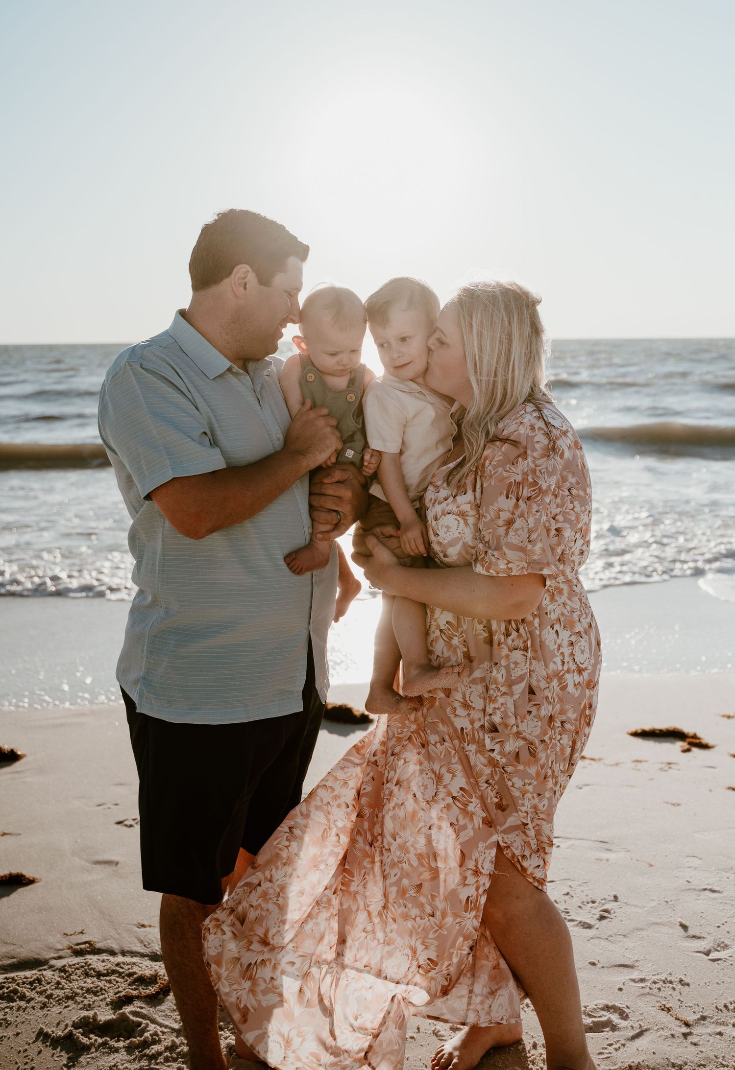 Family shares tender moment together on sunny beach.