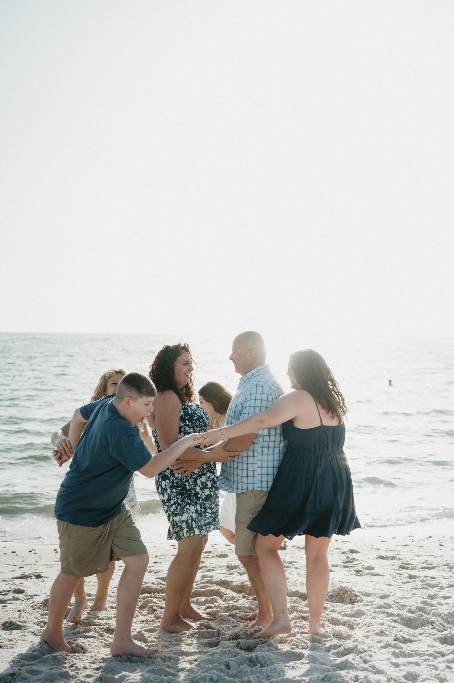 Group of people bending down in a line formation on a beach during sunset.