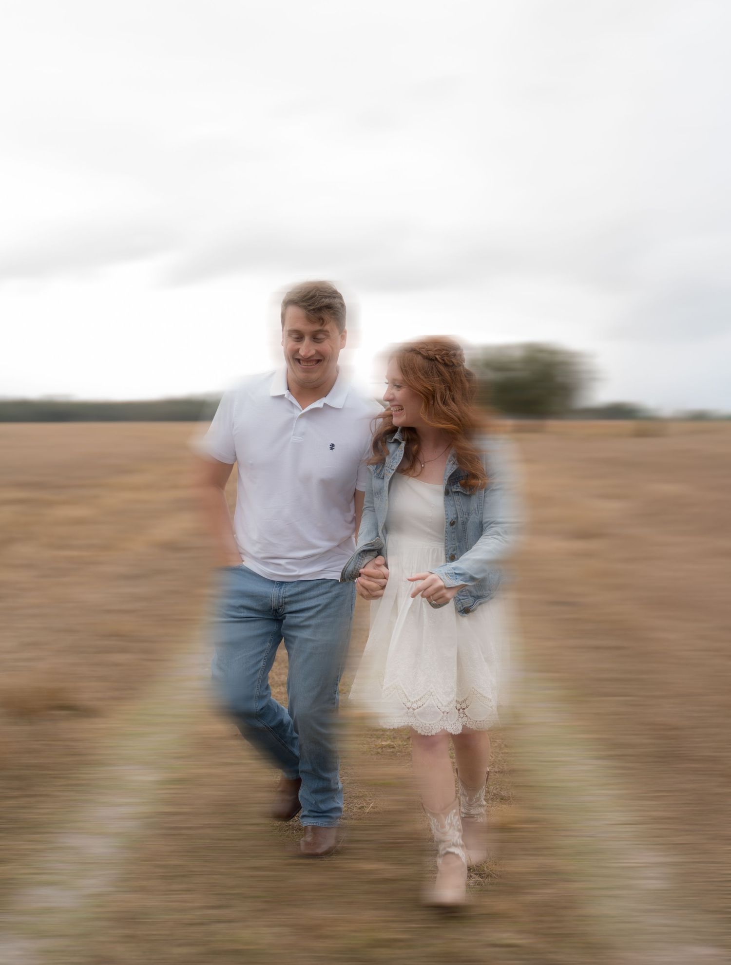 Motion blur photograph of couple walking through golden field.