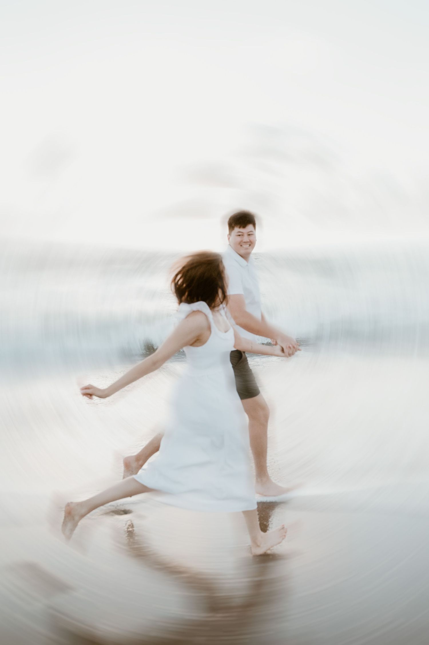 Couple dancing together on a beach with a dreamy motion blur effect creating an ethereal atmosphere.
