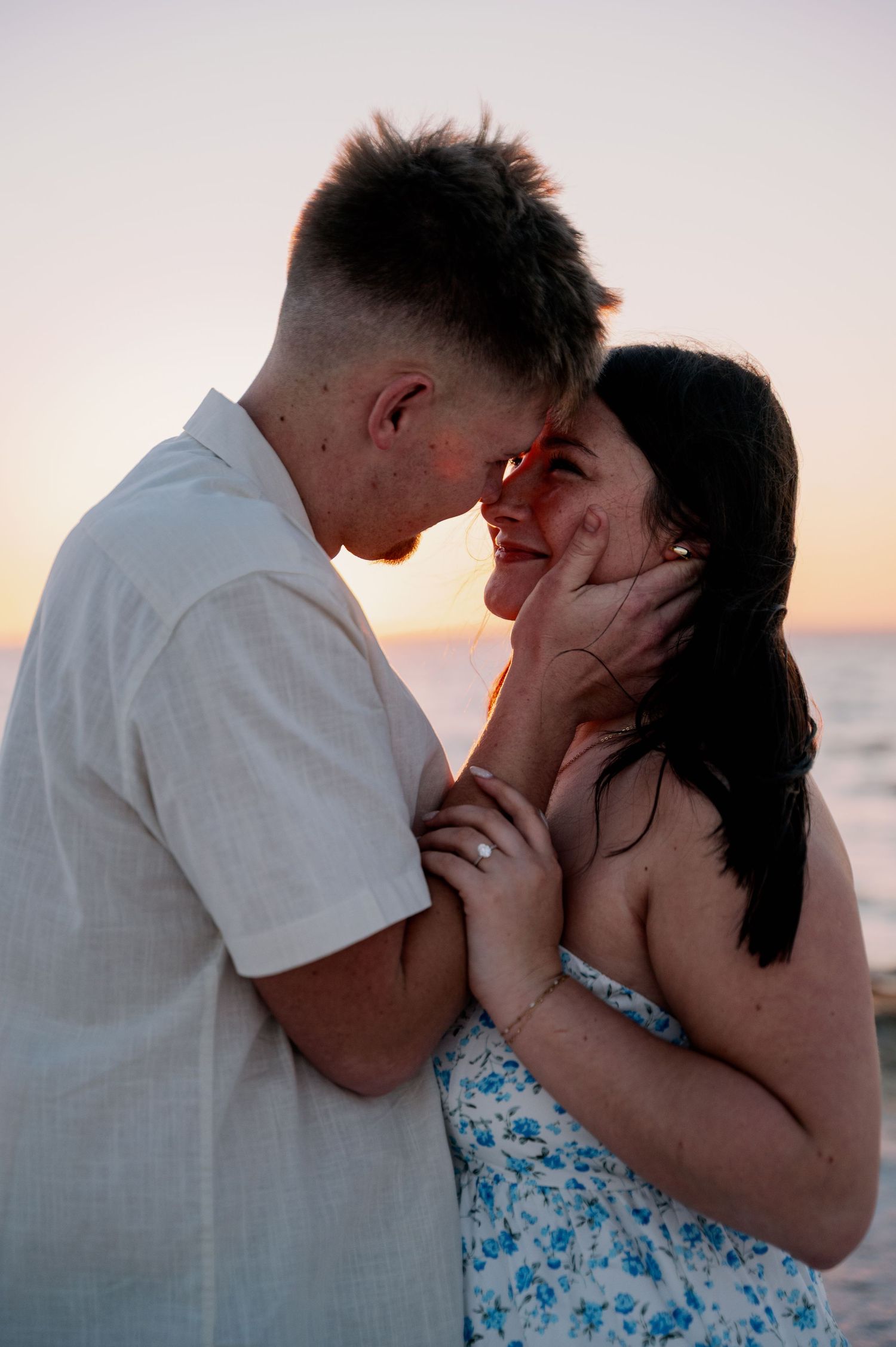 Intimate beach engagement photos with couple sharing tender moments at sunset.
