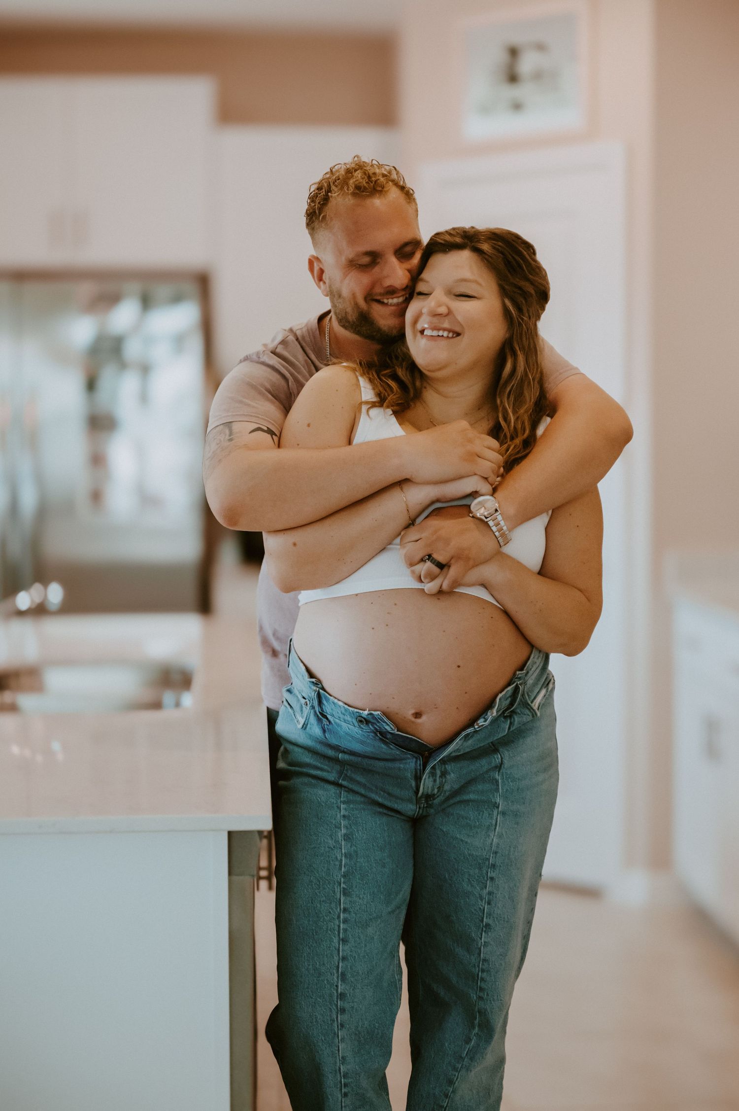 Intimate maternity moment captured in modern kitchen setting.