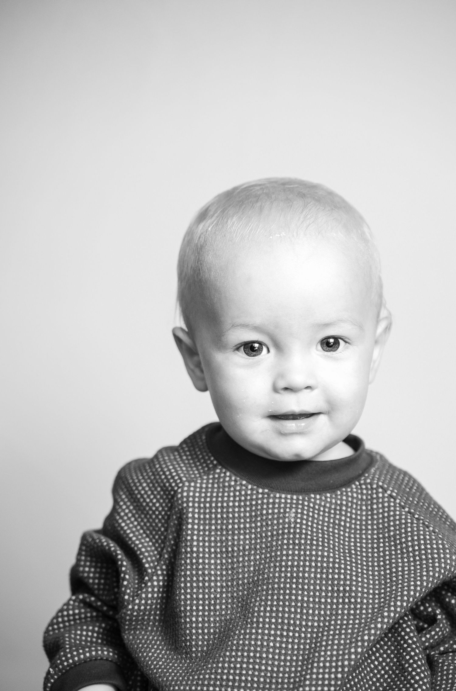 Black and white close-up portraits of an infant wearing a patterned sweater.