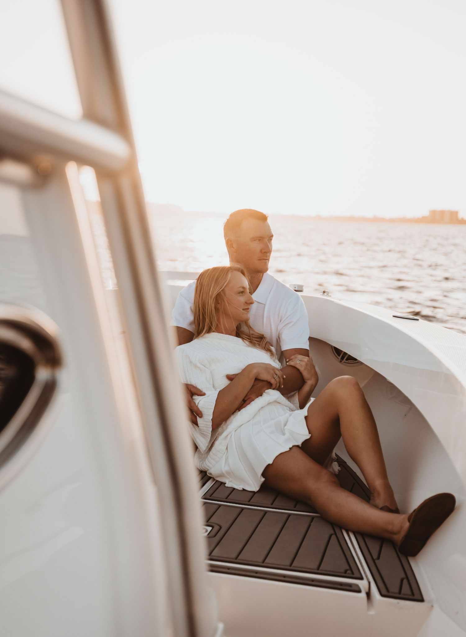 Couple relaxing on boat deck during golden hour sunset.