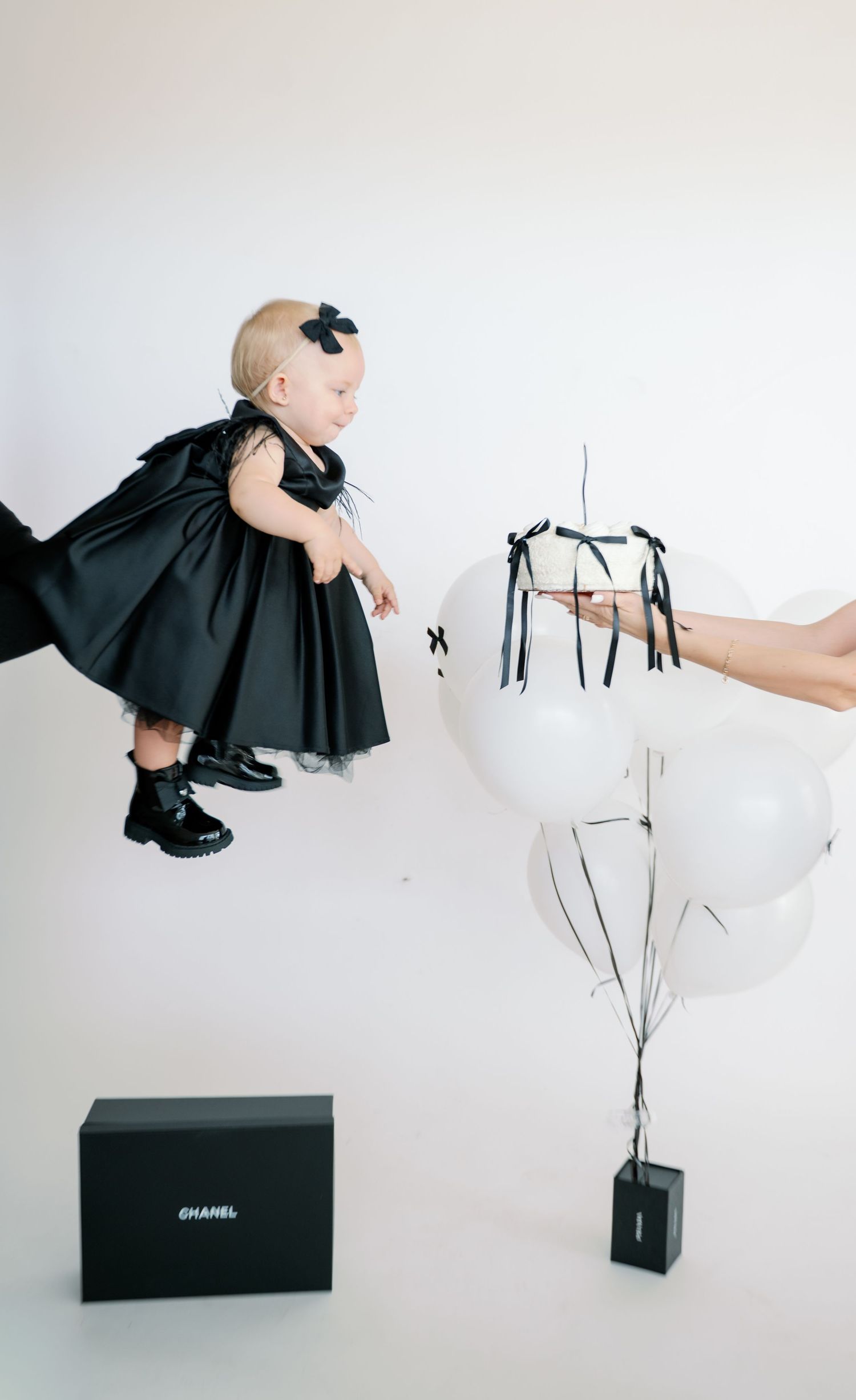 Artistic black and white photo series featuring a black dress and Chanel shopping bags against white background.