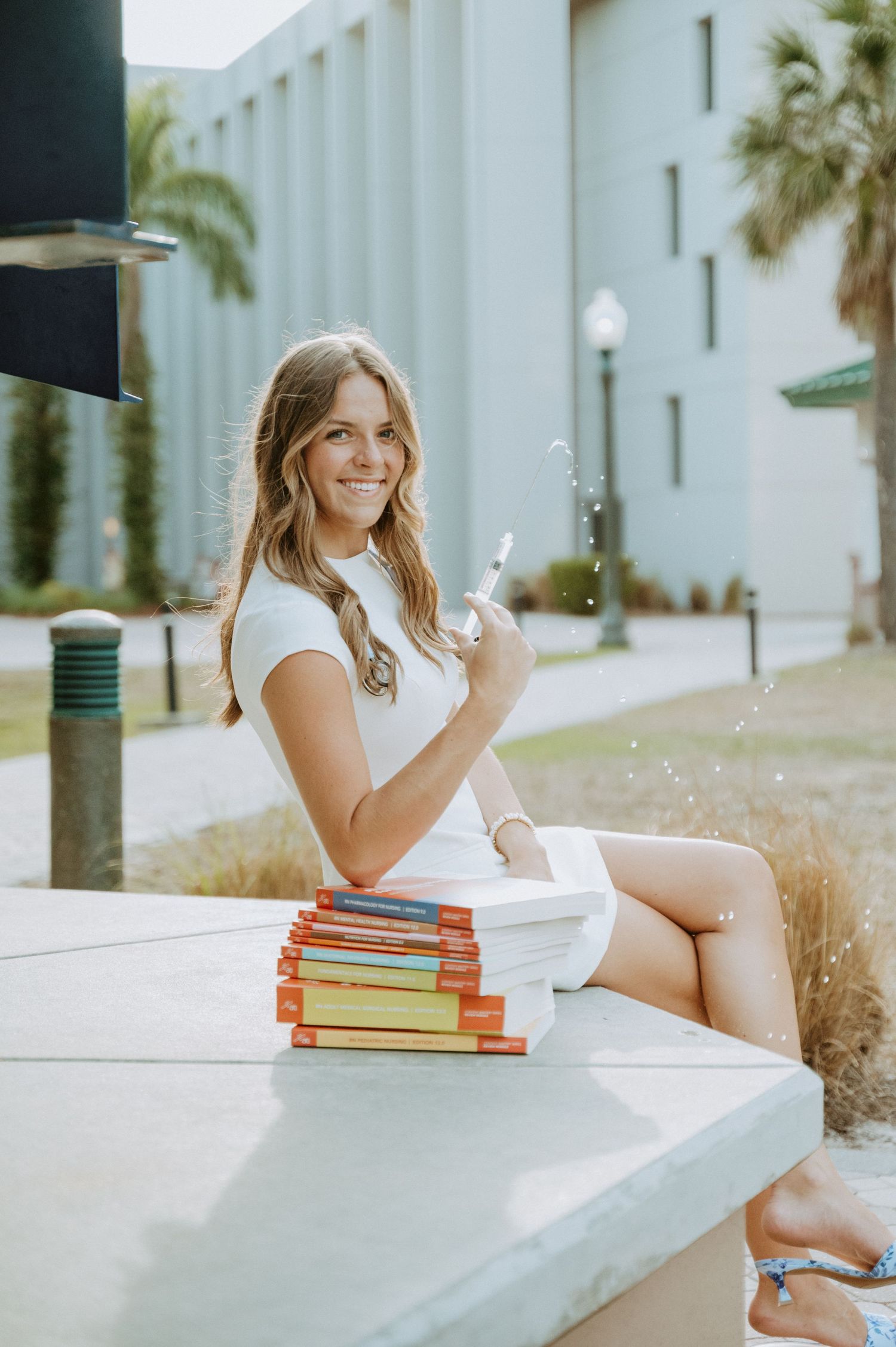 A student sits with textbooks outdoors on campus.