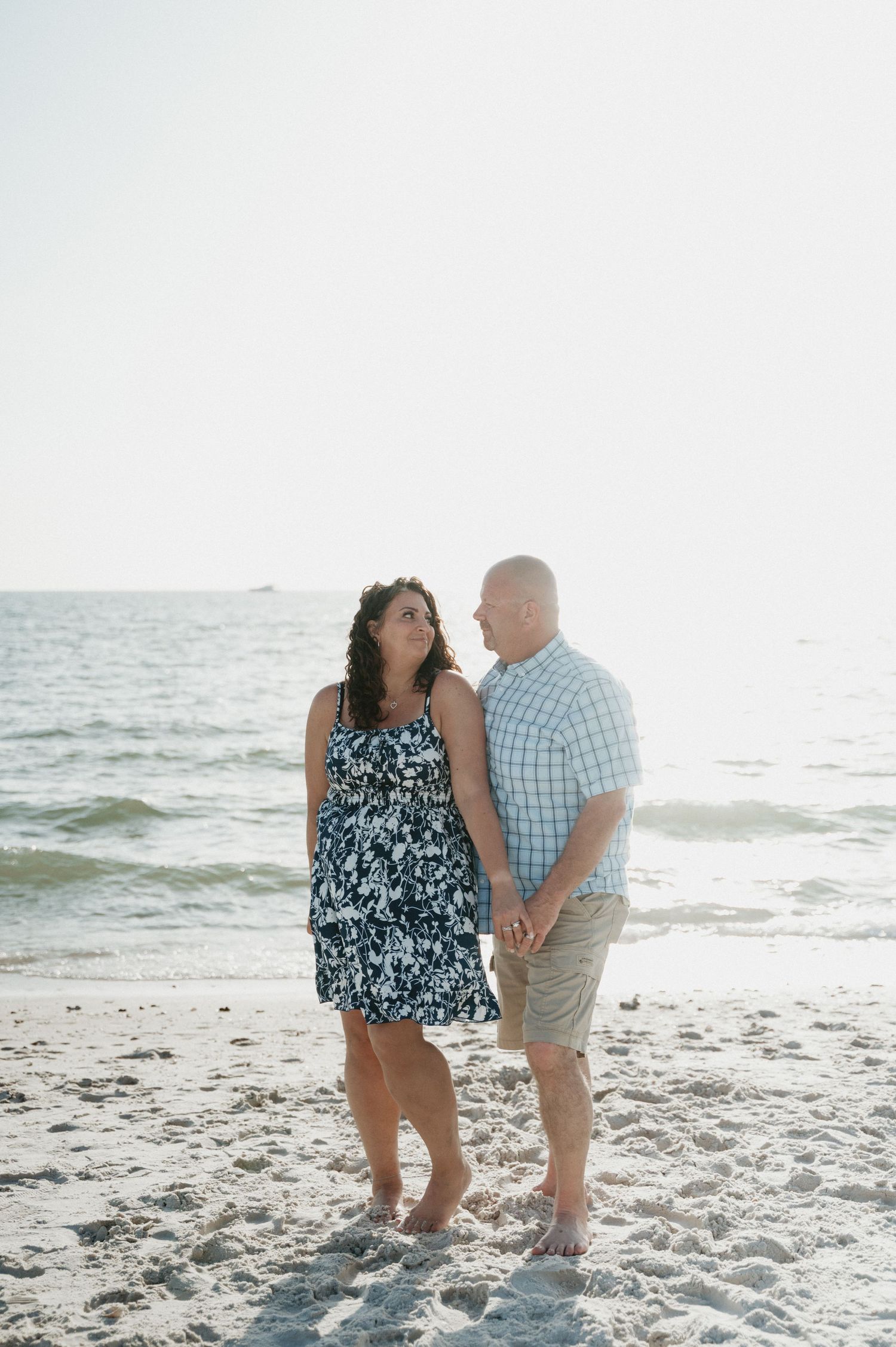 Couple sharing a romantic moment on sandy beach at sunset.