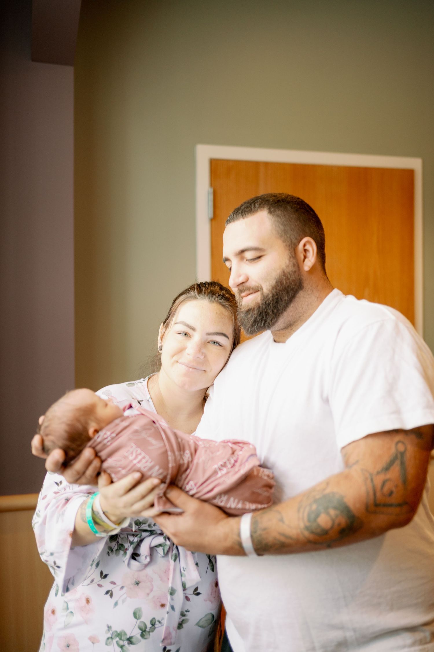 Intimate moment between couple holding a newborn in a hospital room.