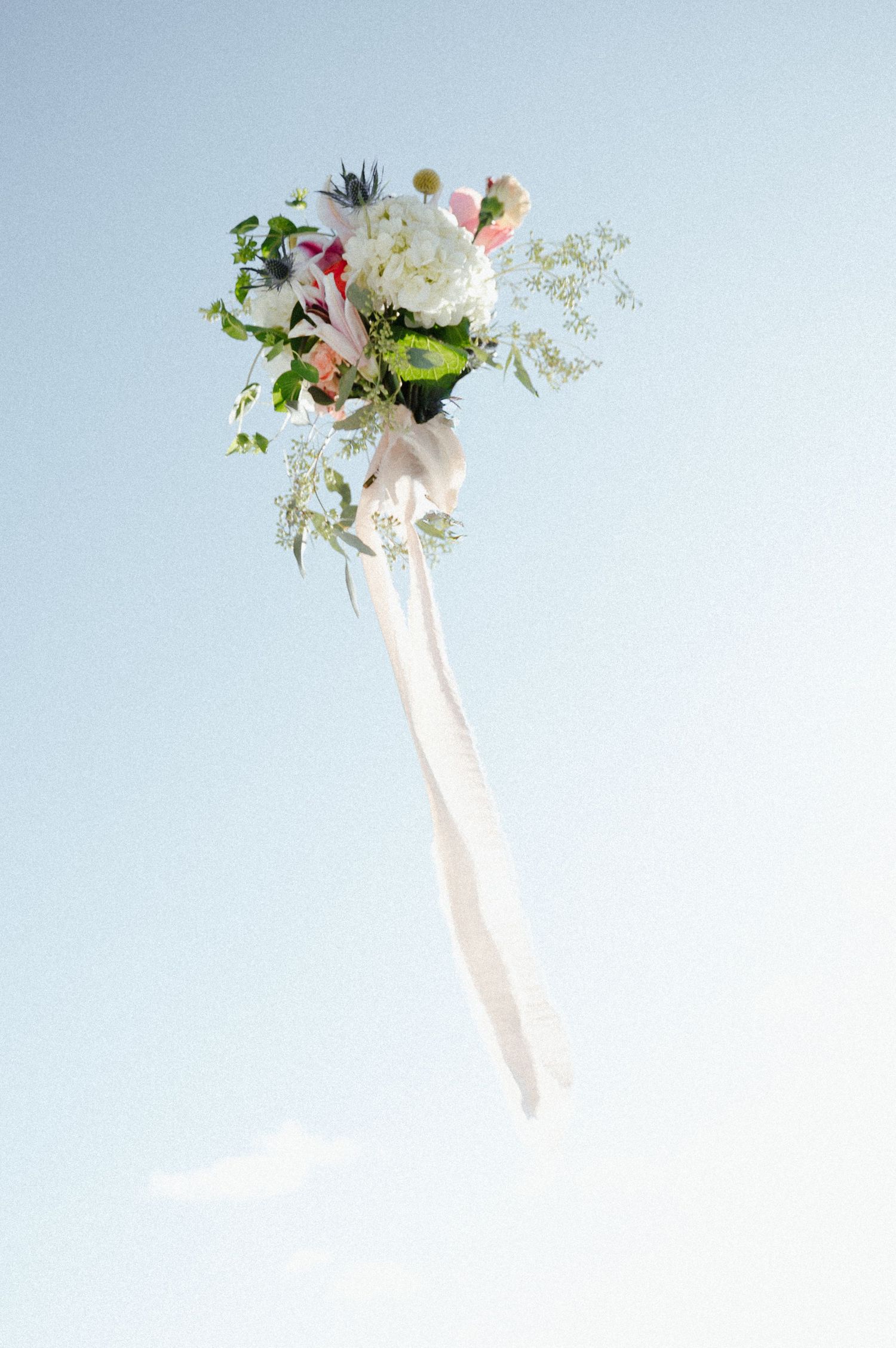 Delicate floral bouquet with white and pink flowers against light blue background.