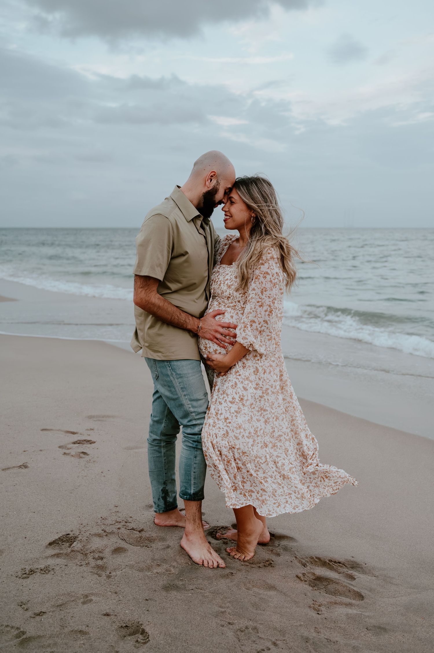 Romantic couple sharing intimate moments on a cloudy beach.