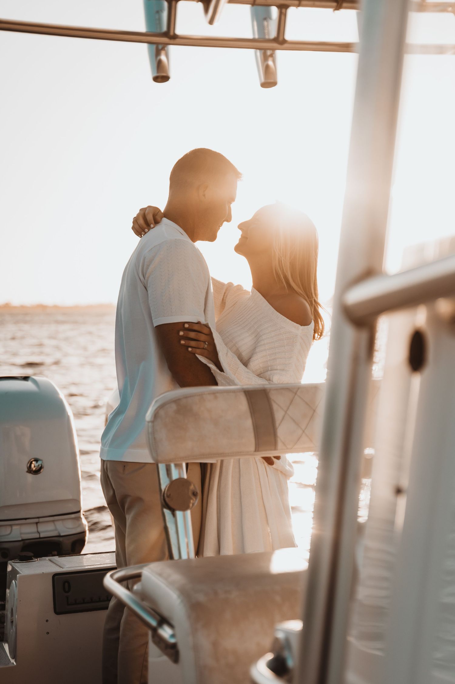 Romantic silhouette of a couple embracing on a boat during golden hour sunset.