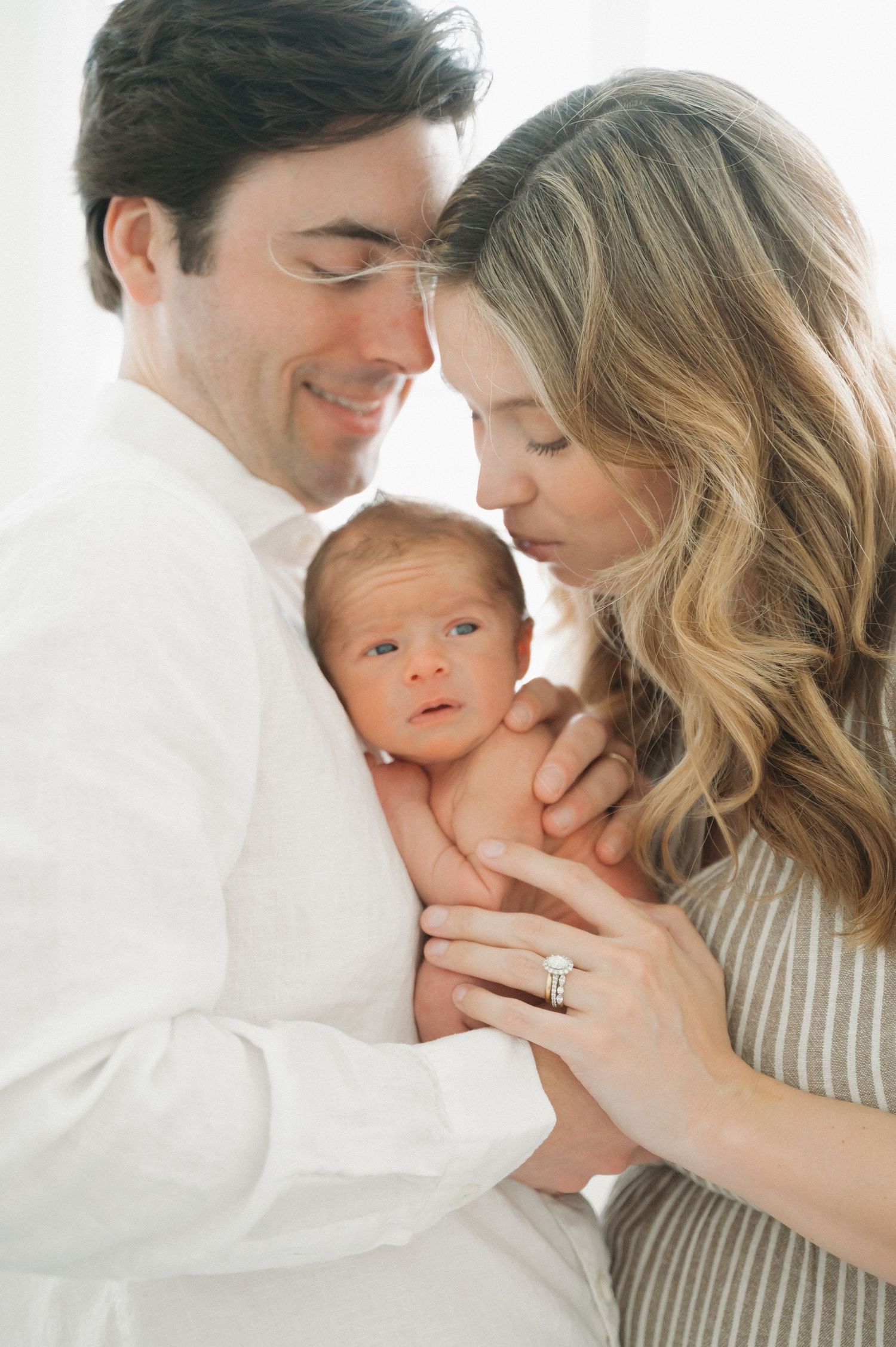 Intimate family portrait with newborn baby in soft natural light.