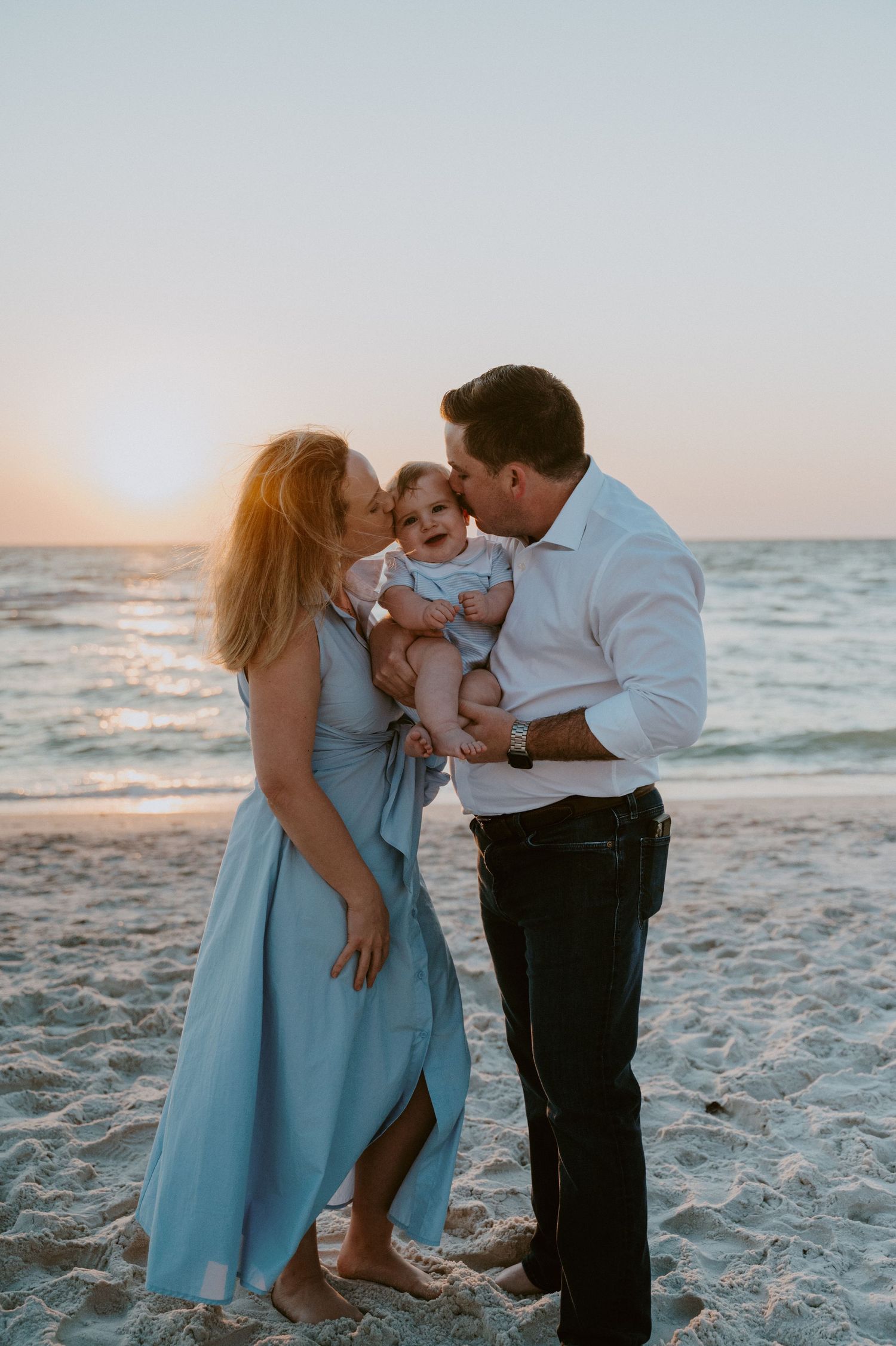 Intimate family moment captured on a white sandy beach at sunset.