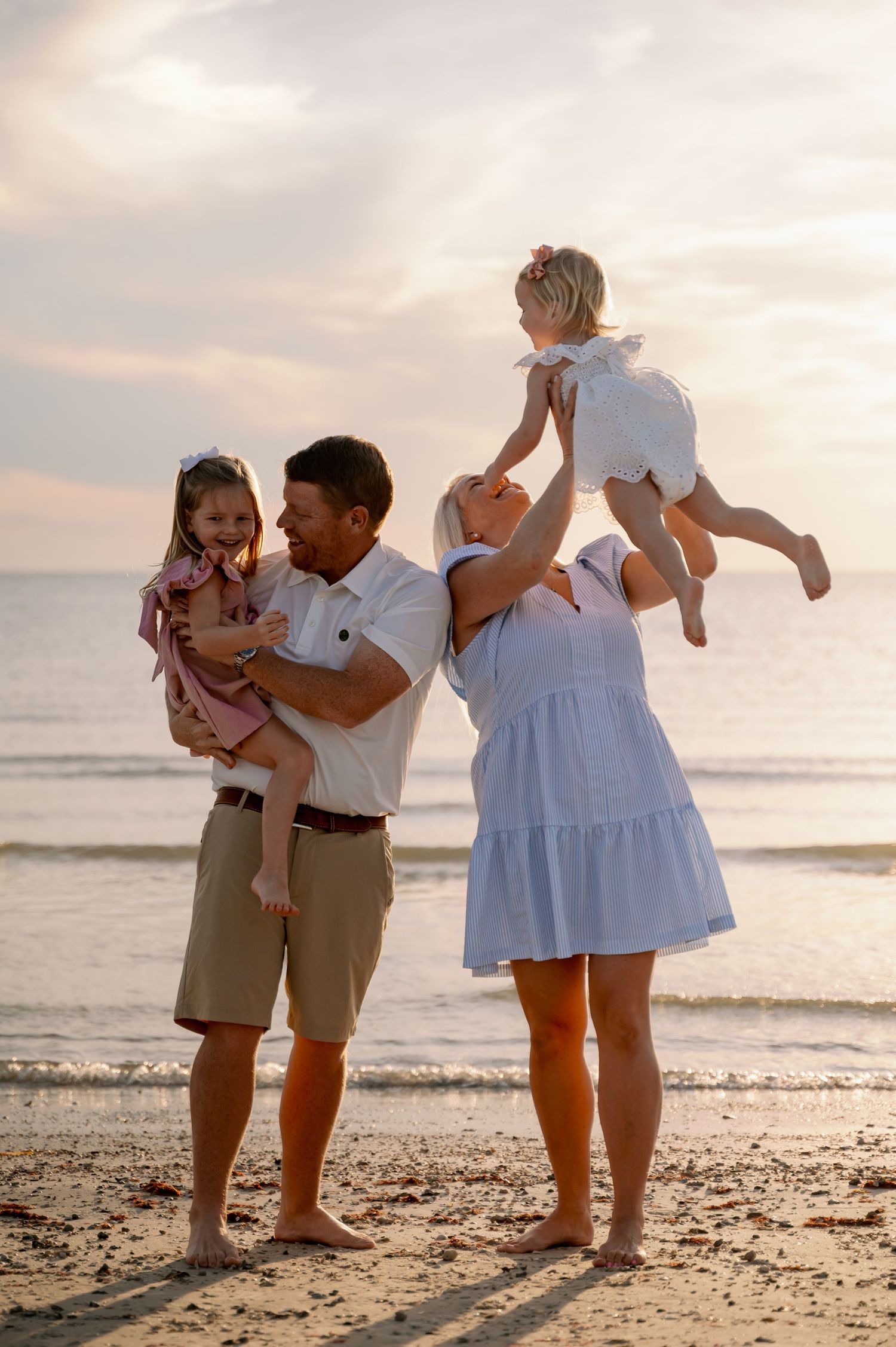 Playful family photos on the beach at golden hour showing joyful interactions.