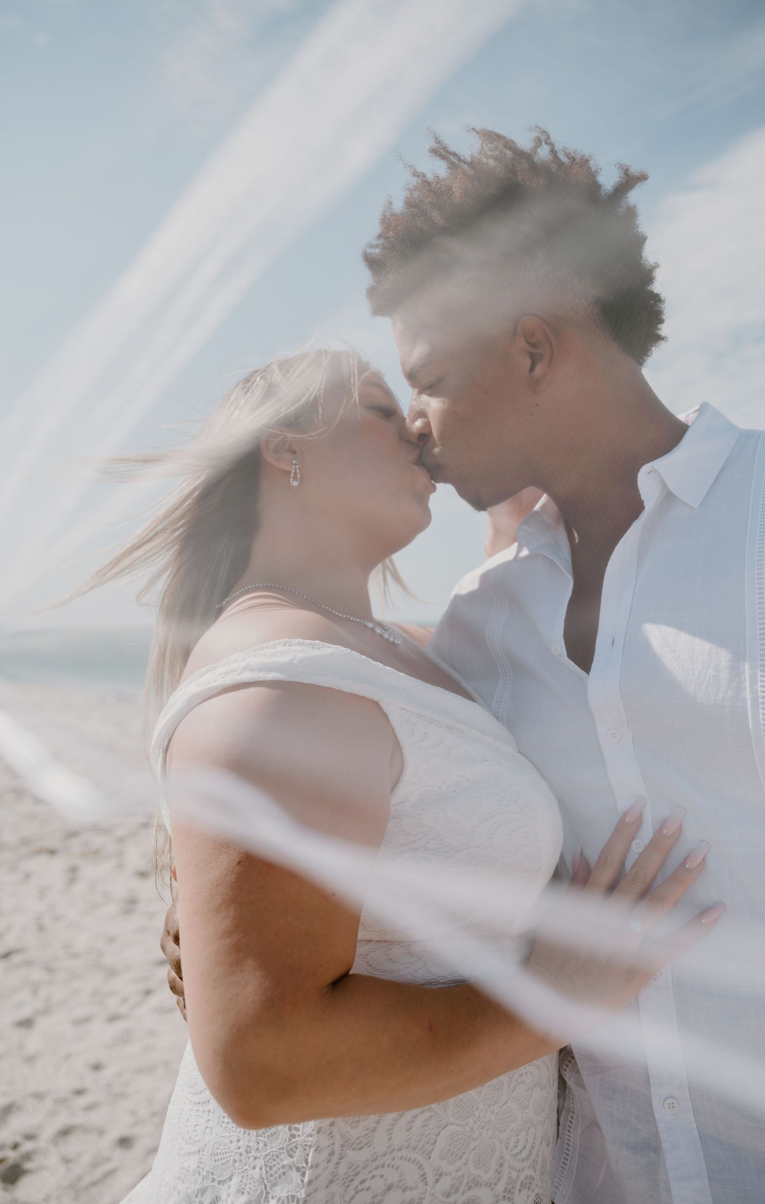 Ethereal beach wedding portraits with flowing veil catching the ocean breeze.