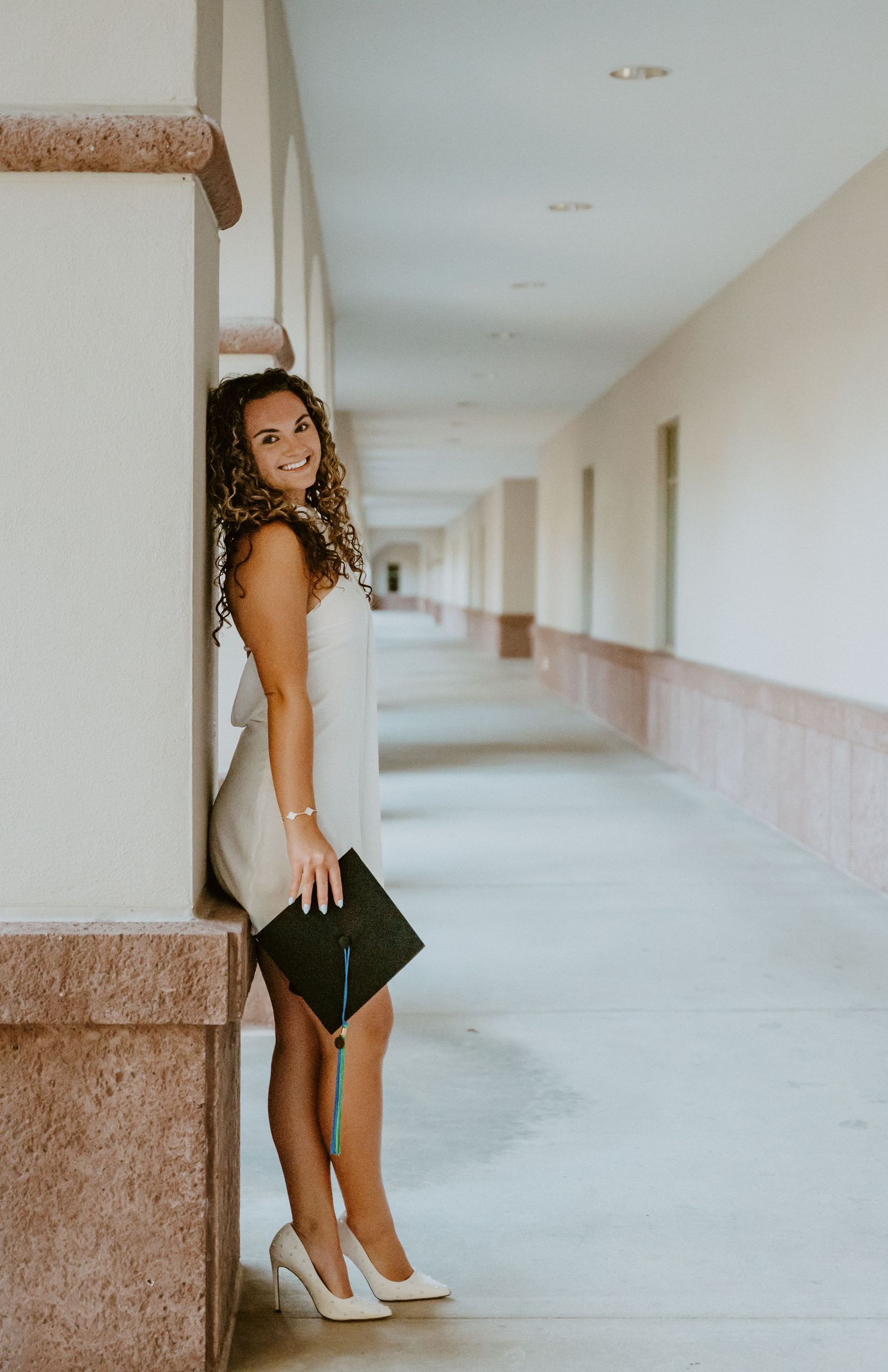 Woman in formal attire posing in an empty hallway.