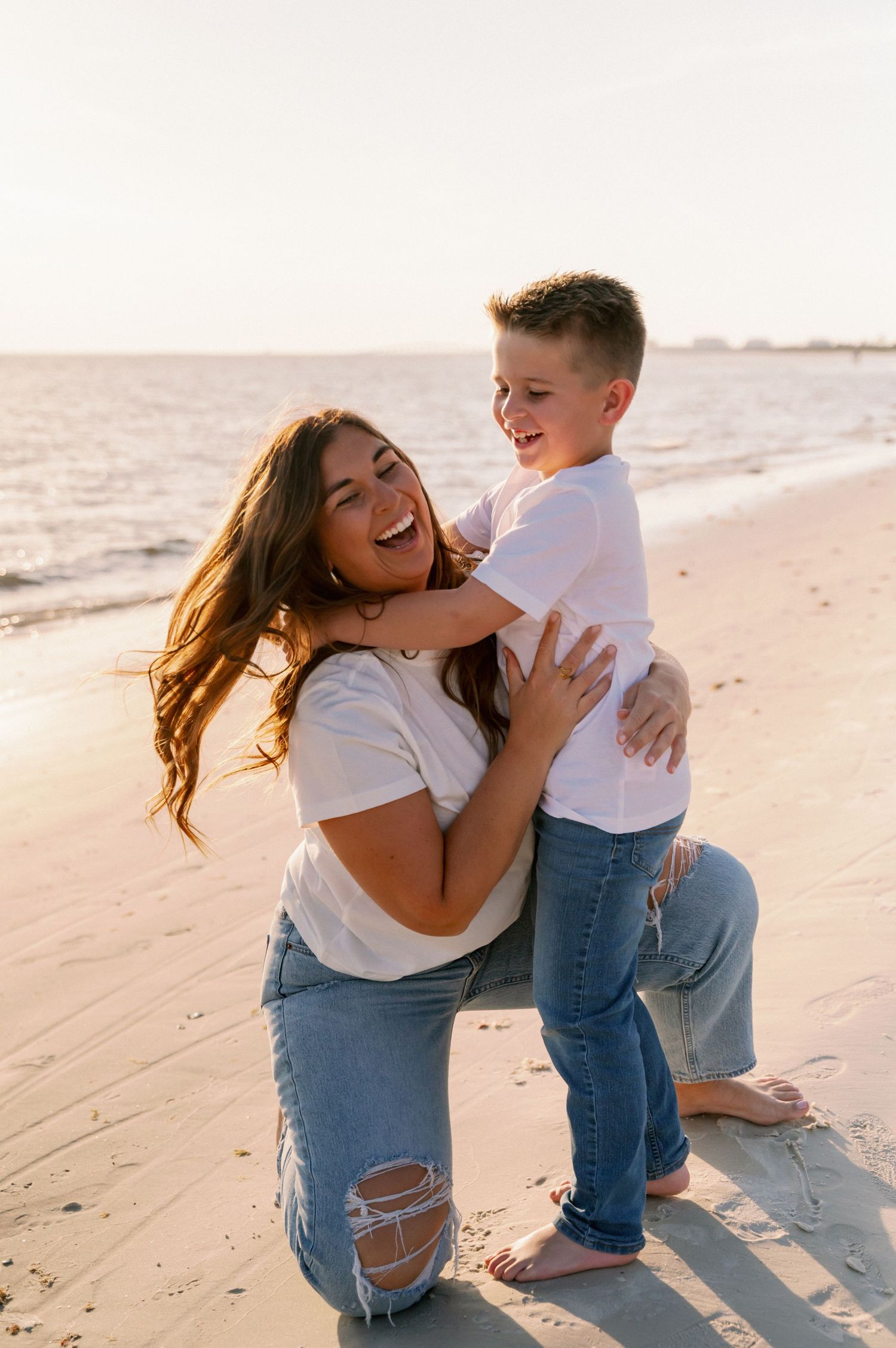 Playful mother and child moment captured on sunny beach.