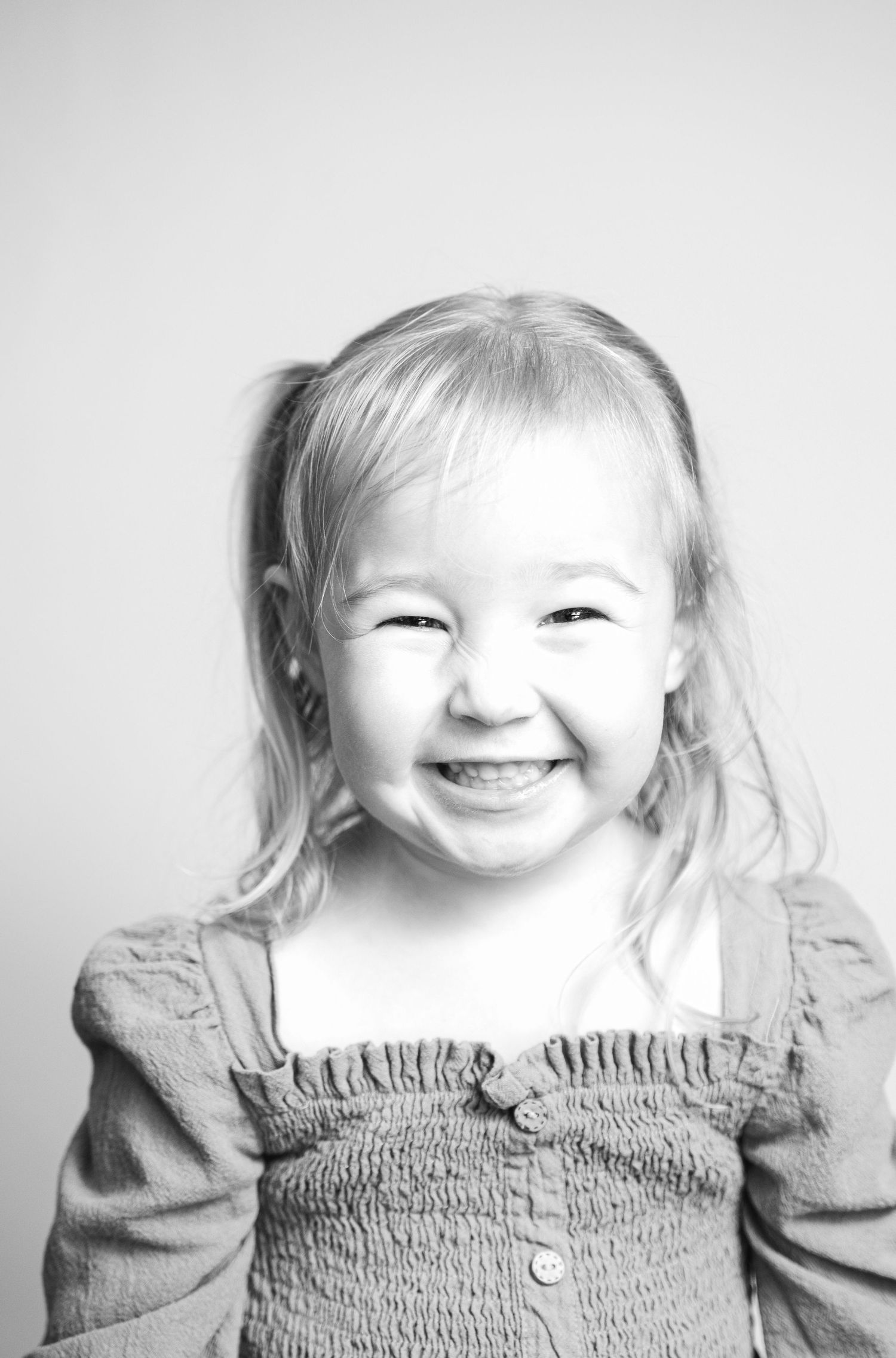 Black and white portrait series showing joyful expressions in a smocked dress.