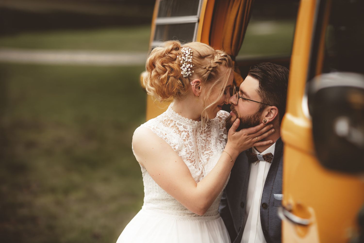 Romantic wedding moment against vintage yellow van in outdoor setting.