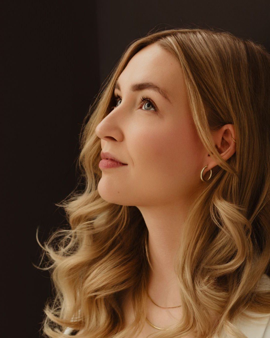 A woman with blonde wavy hair gazes upward in a series of artistic profile portraits against a dark background.