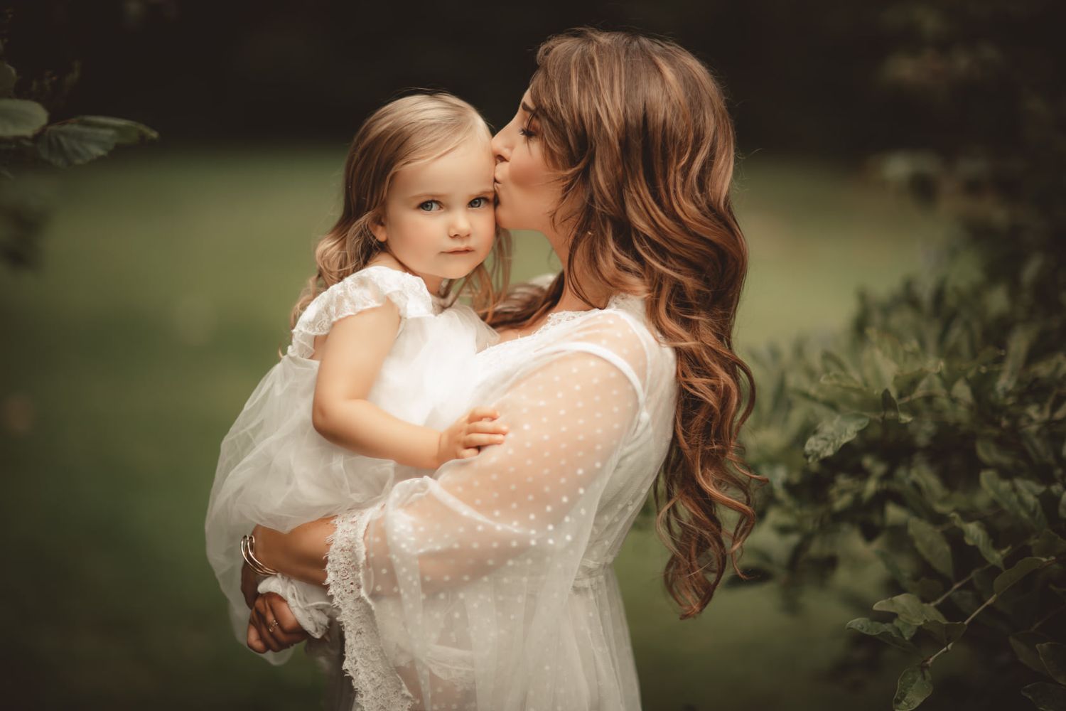 Couple shares tender embrace during outdoor wedding photoshoot in natural setting.