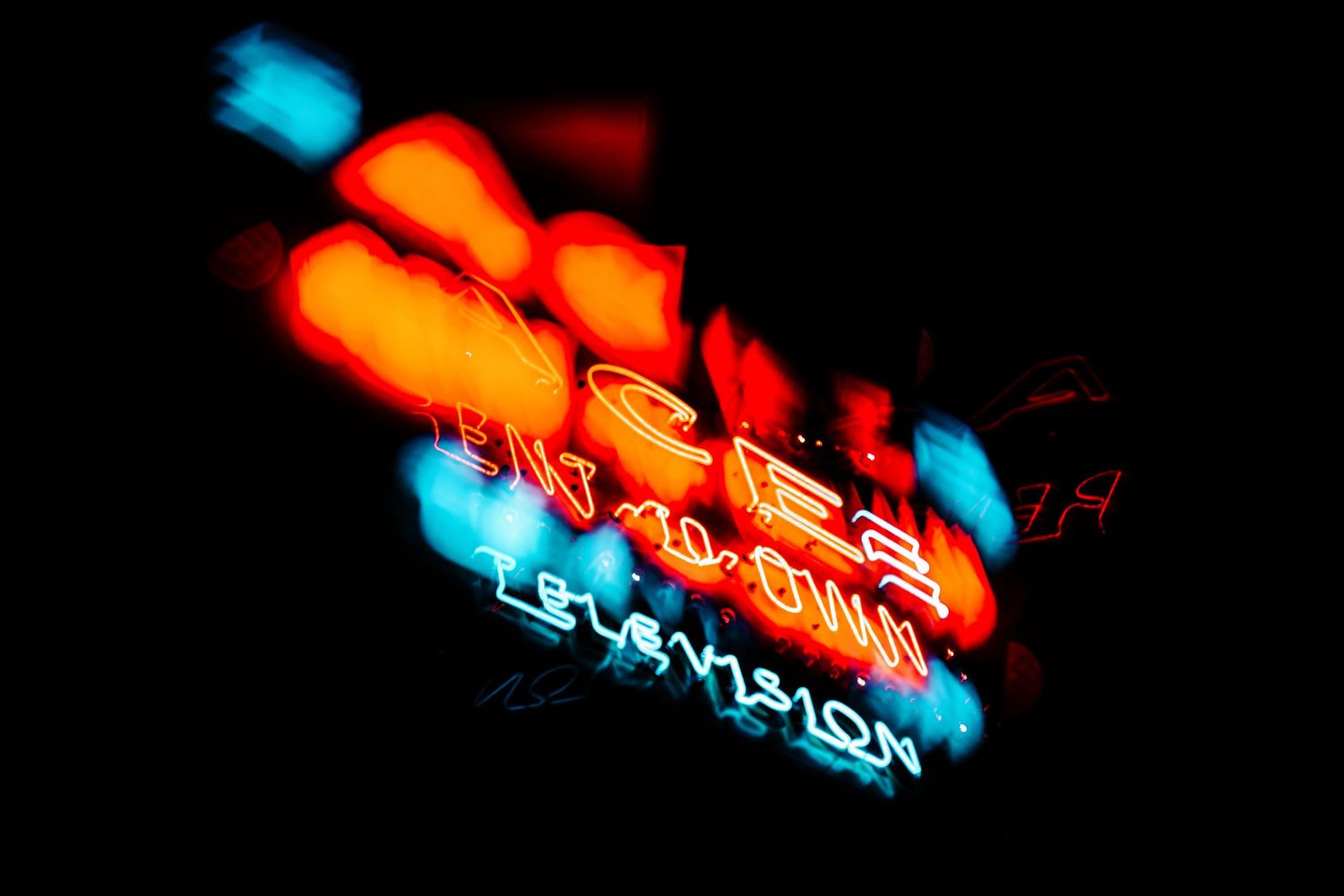 Motion blurred neon sign glowing in orange and blue colors with abstract light trails.