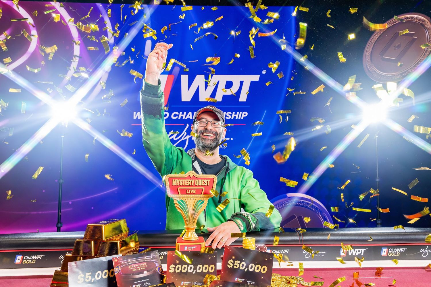 Man celebrating WPT World Championship poker tournament win with confetti, trophy, and prize checks on stage.