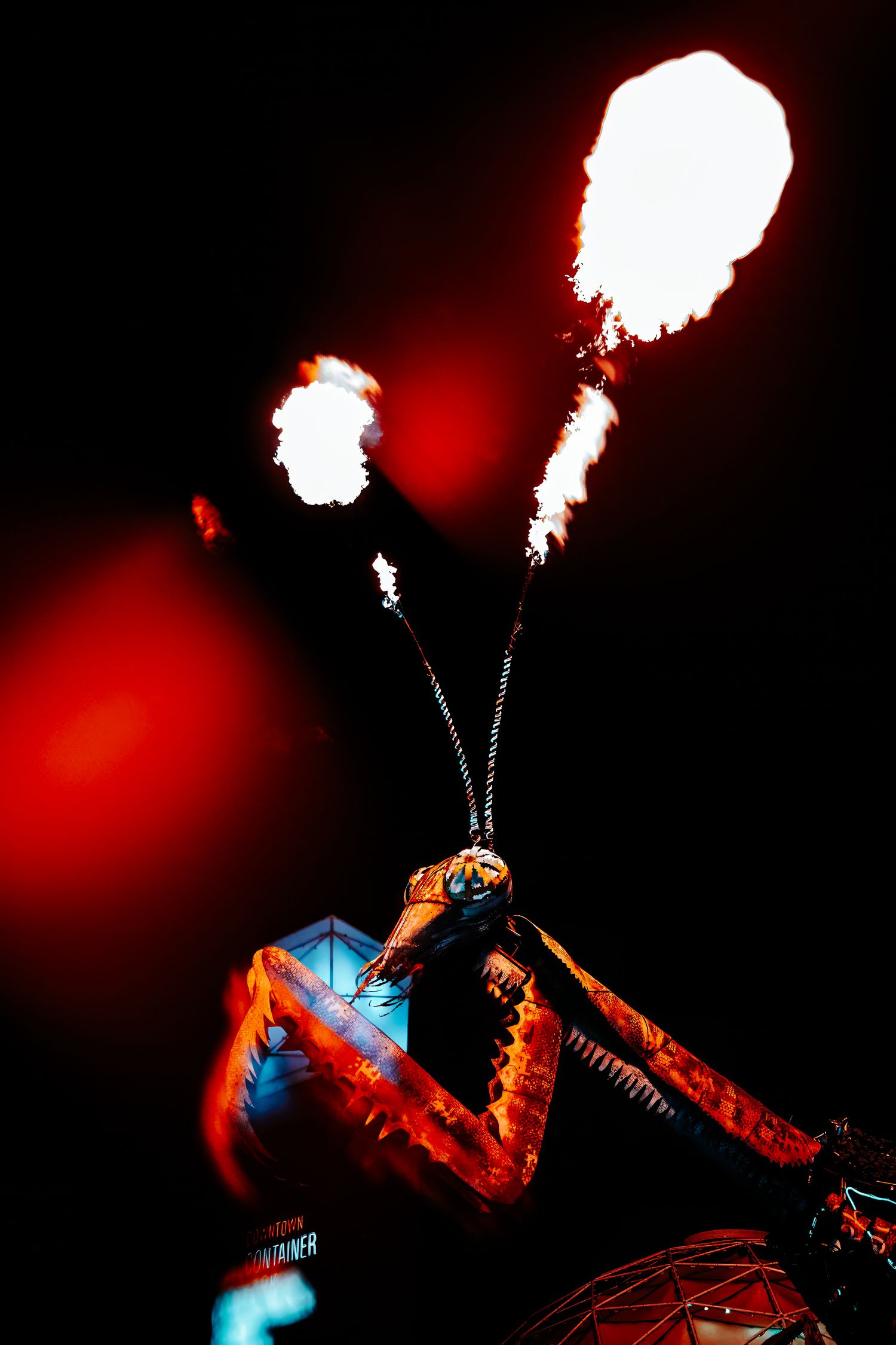 A dramatic motorcycle stunt performer shoots illuminated flares into the dark sky while performing on a bike.