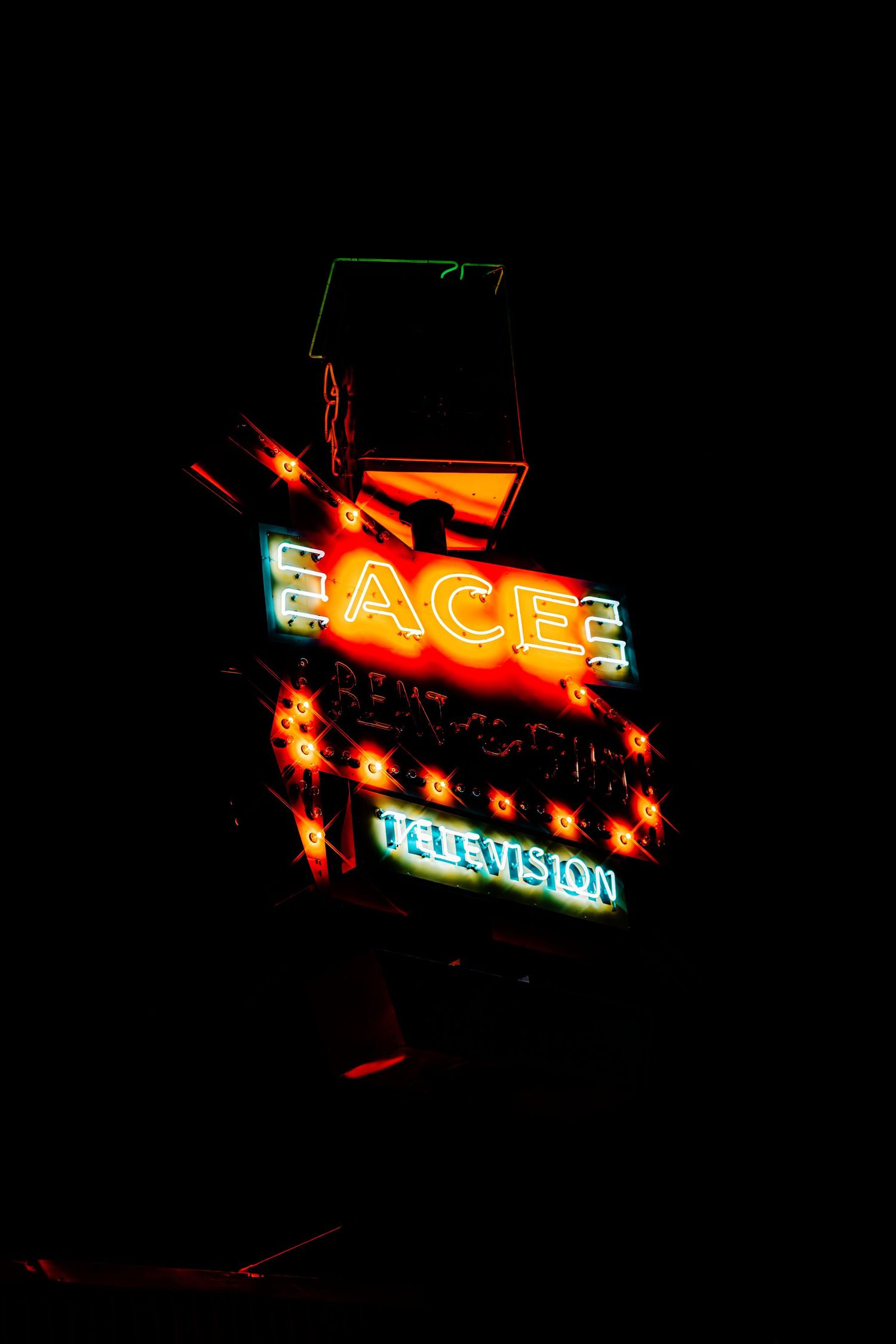 Vintage neon sign displaying 'EAGLE TELEVISION' glows in red and blue against dark night sky.