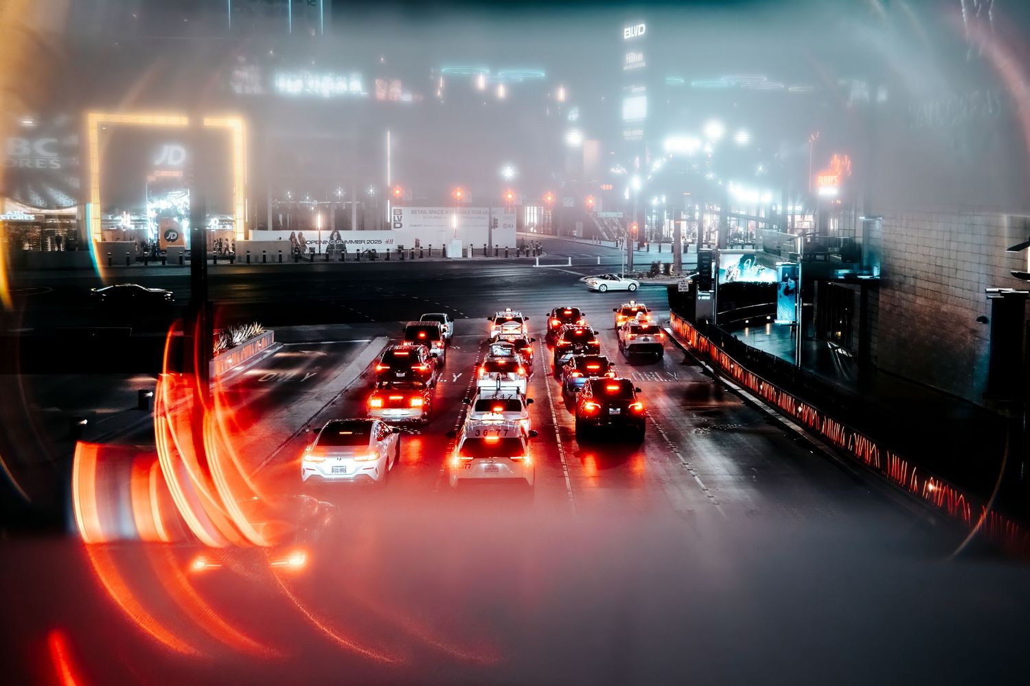 Timelapse photography of cars and traffic lights creating colorful light trails on a dark city street at night.