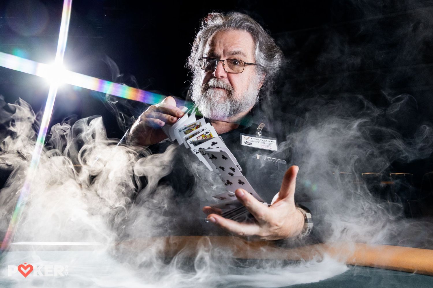 Scientist demonstrating experiment with dry ice smoke effects, holding equipment under colorful light beams in dark studio.