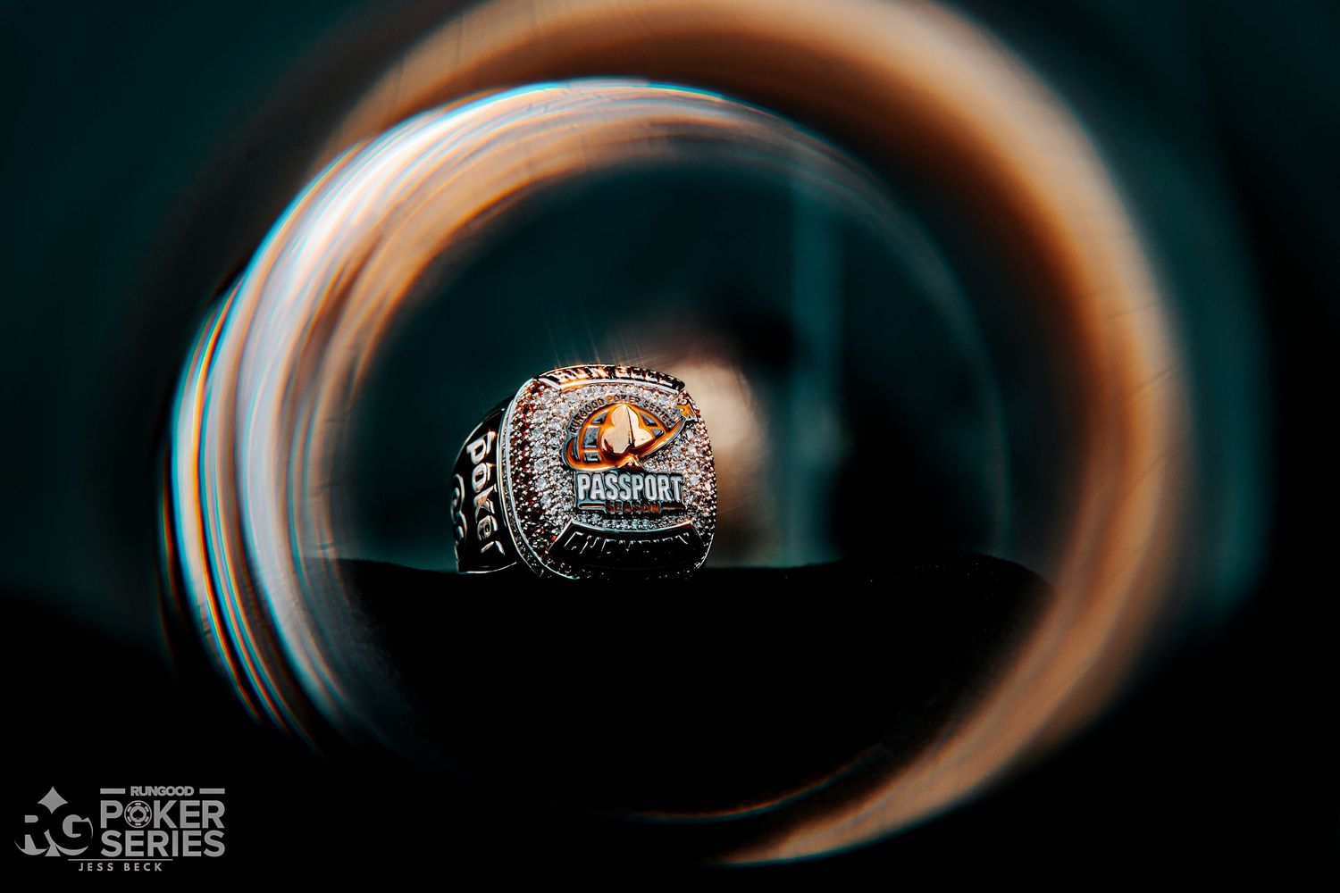 Close-up of a Poker Series championship ring with amber stone, captured through a circular bokeh lens effect.