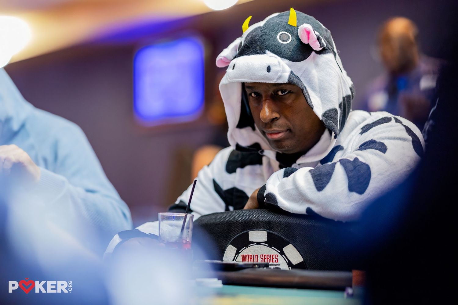 Man wearing a cow costume onesie sits at a poker table during a World Series of Poker tournament event.