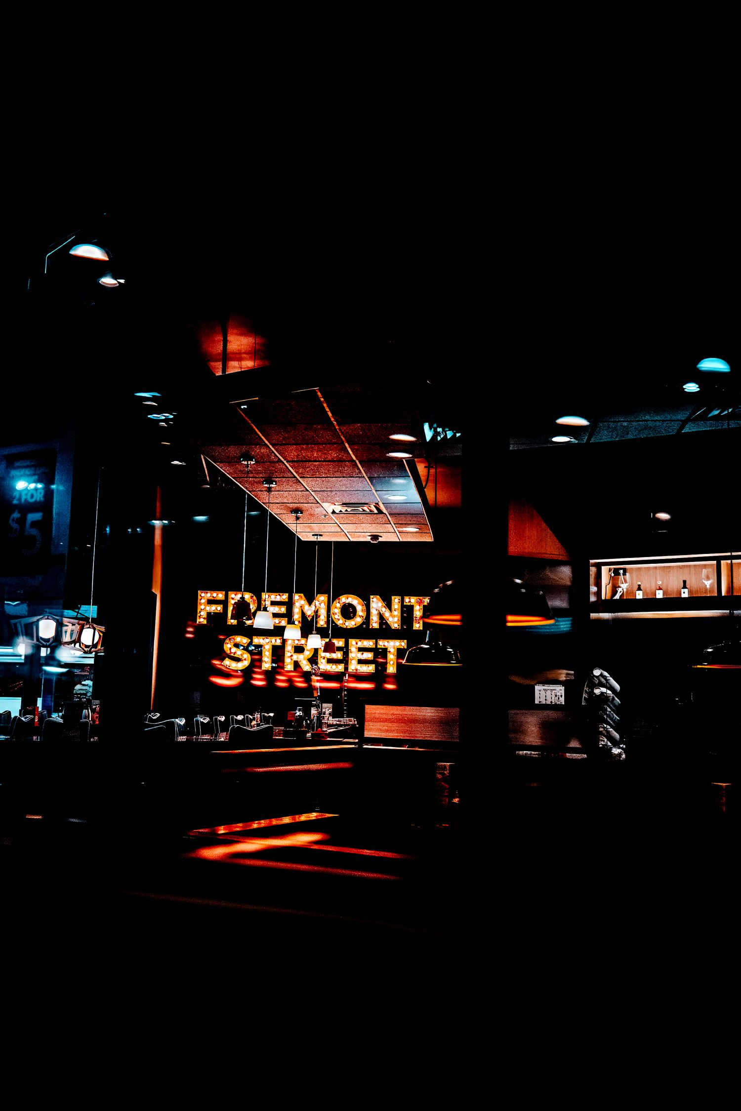 Dark urban street scene at night with illuminated neon signage reading FREMONT STREET in multiple mounted displays.