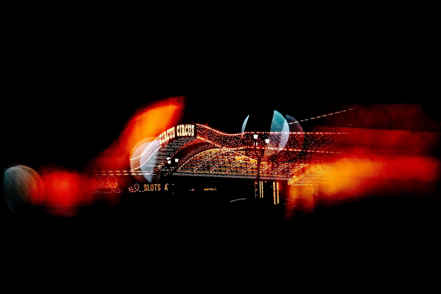 Long exposure night photograph shows red light trails and illuminated bridge structure creating dramatic streaks across dark sky.