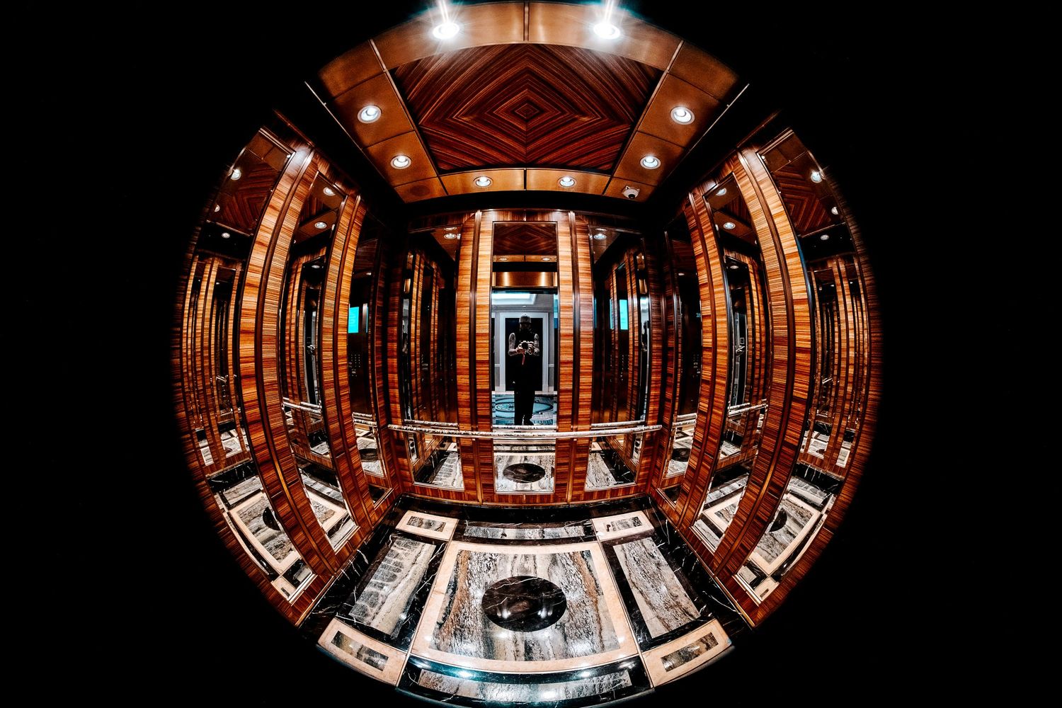 Fisheye lens view of an ornate wooden interior room with marble table and warm amber lighting.