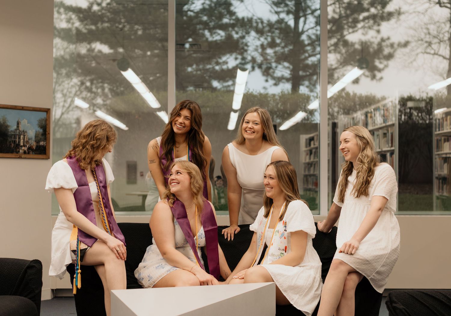 A group of healthcare students in white uniforms and burgundy scrubs gather together in a classroom setting.