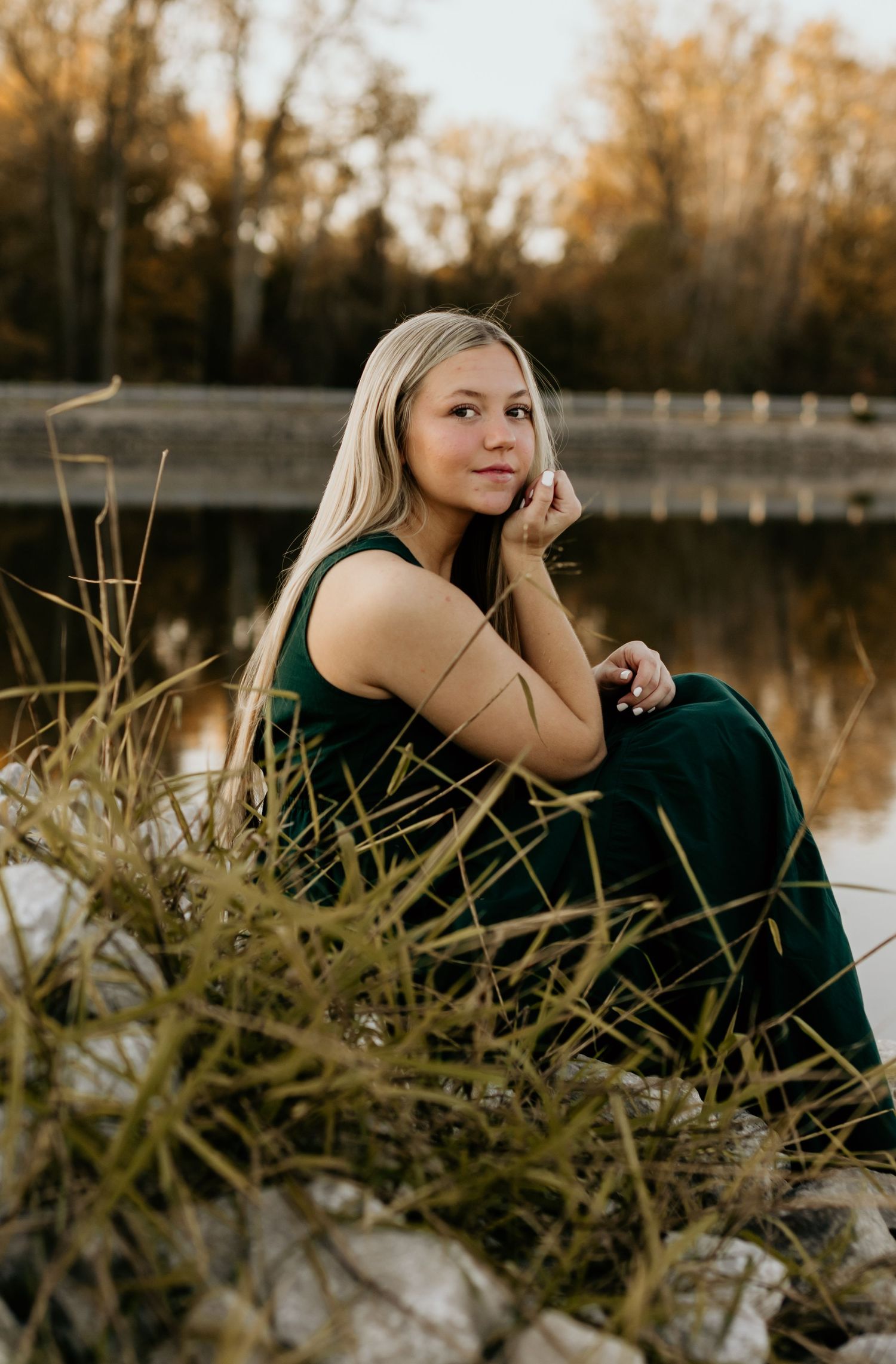 Portrait in emerald dress among lakeside reeds during golden hour.
