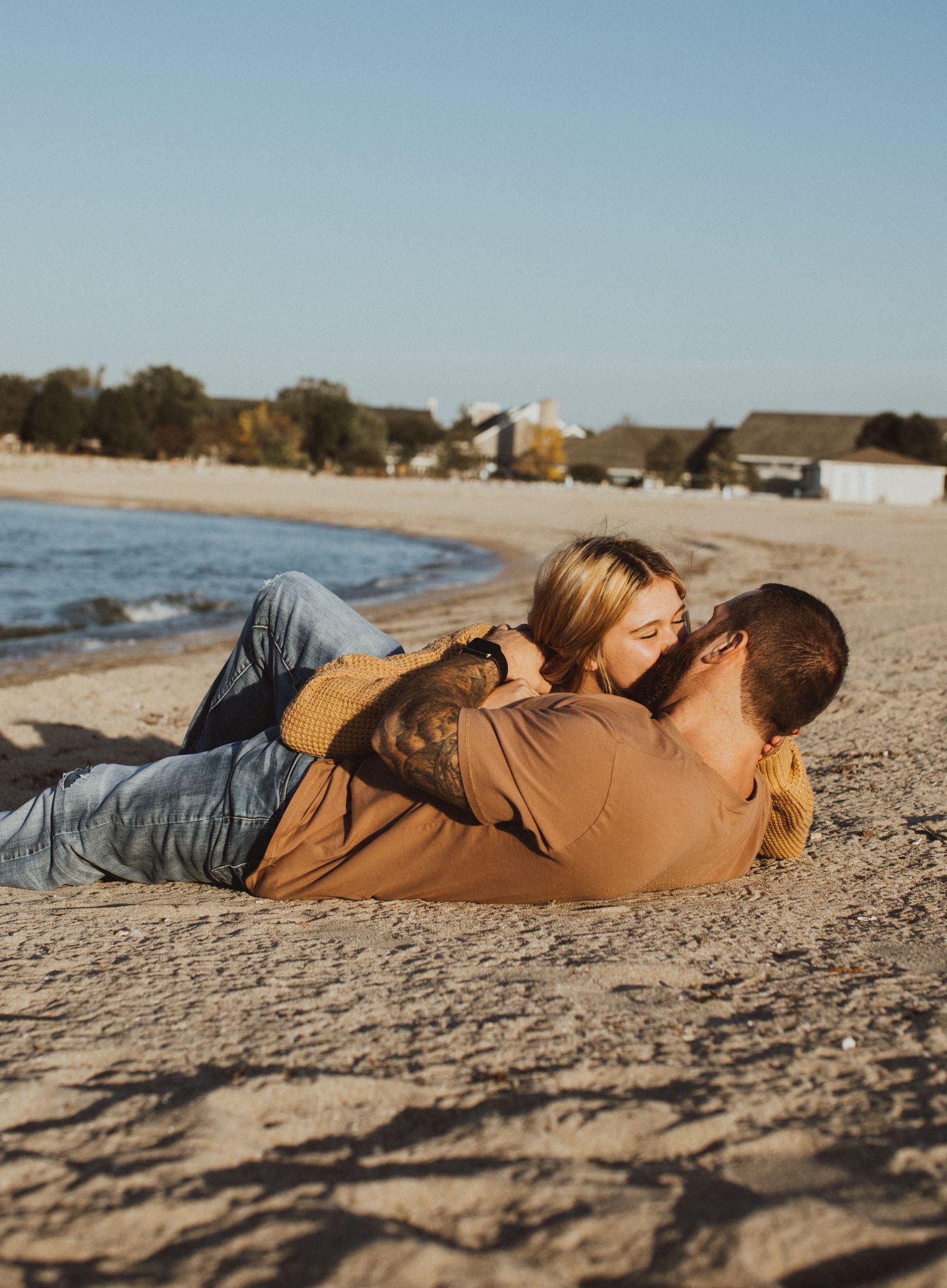 A couple relaxes together on a sandy beach near the ocean.