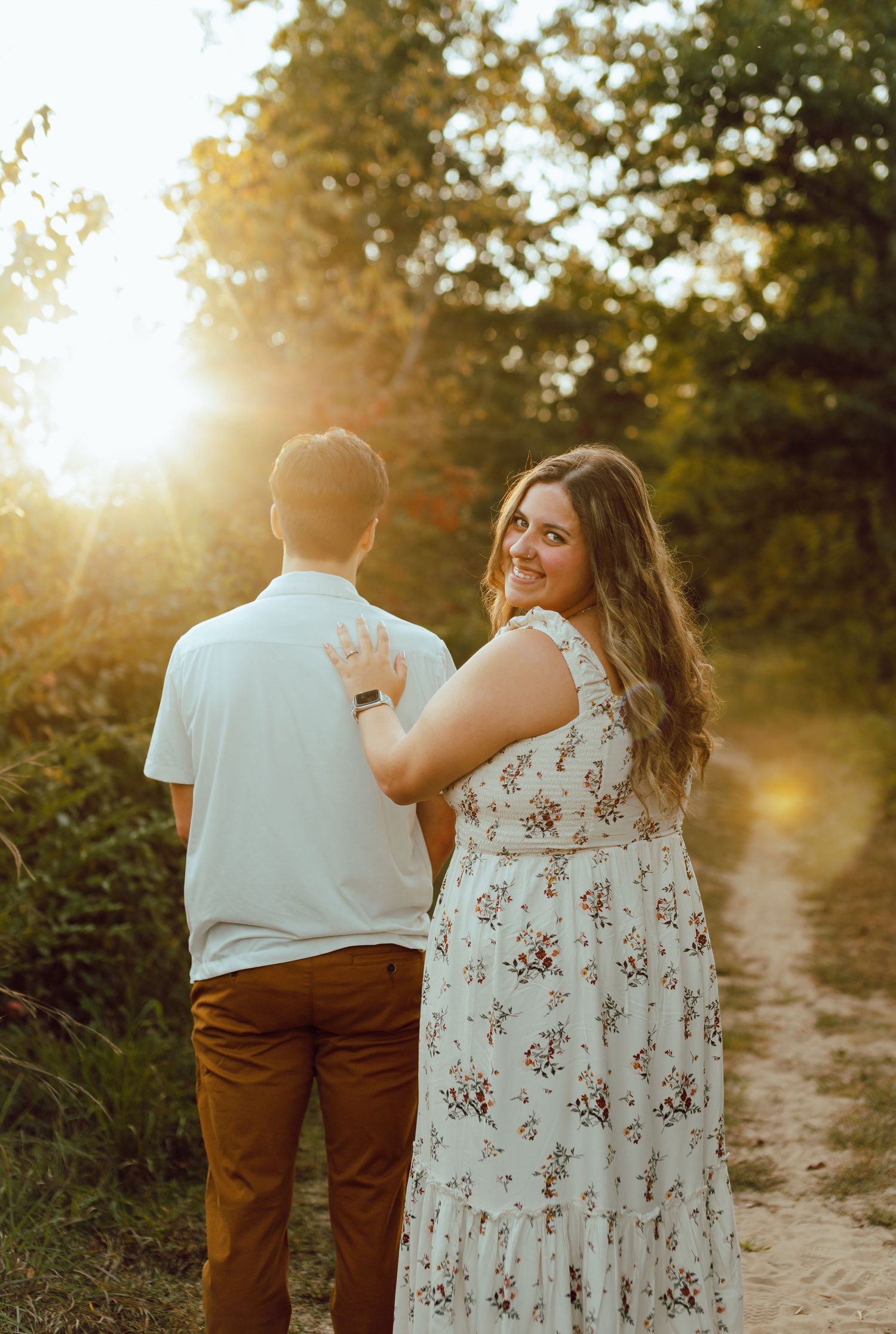 A couple walks along a nature path during sunset.