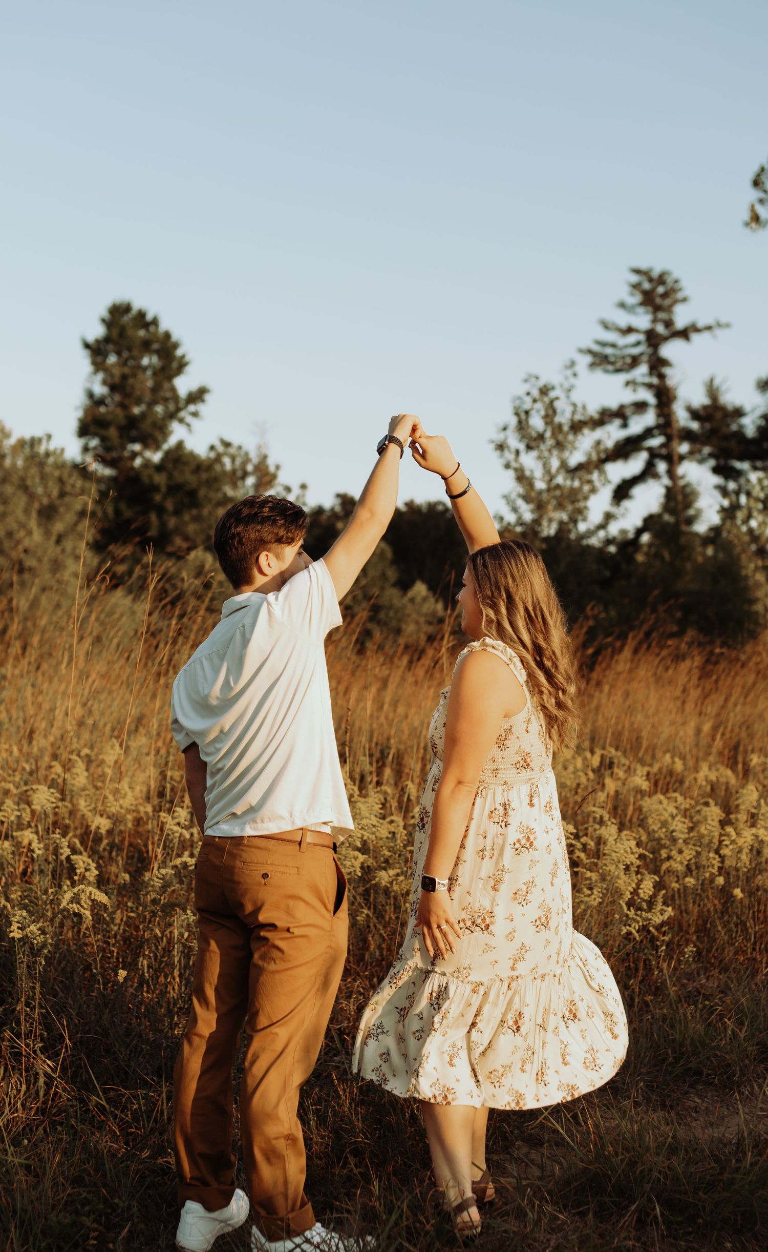 A couple dances in a sunlit meadow with tall grass.