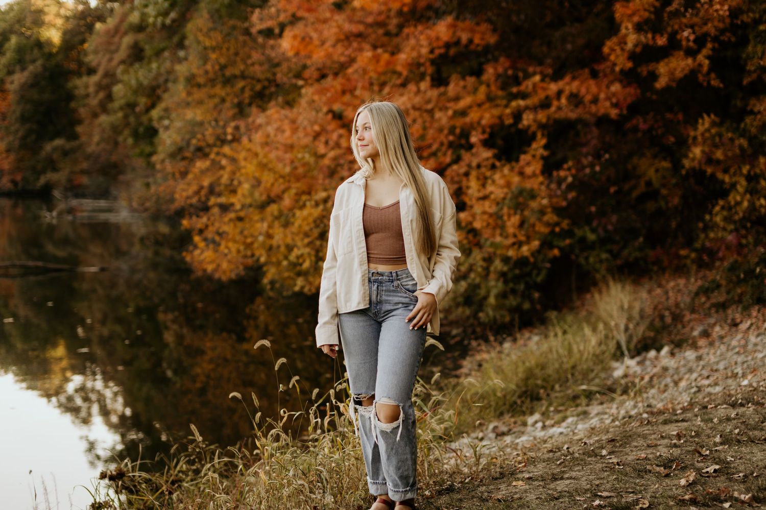 Autumn portrait by a lake with fall foliage reflecting in water.