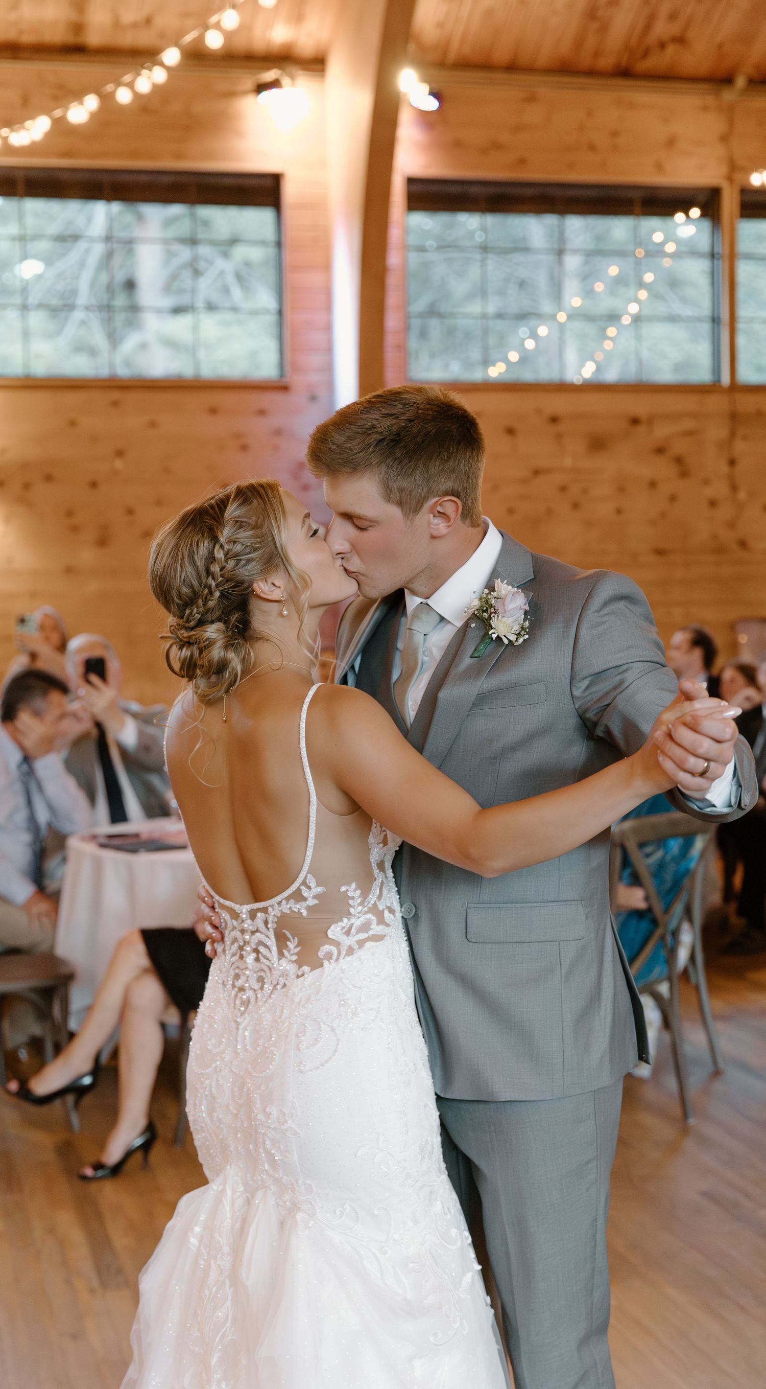 A romantic first dance sequence at a rustic barn wedding venue with twinkling lights and wooden walls.