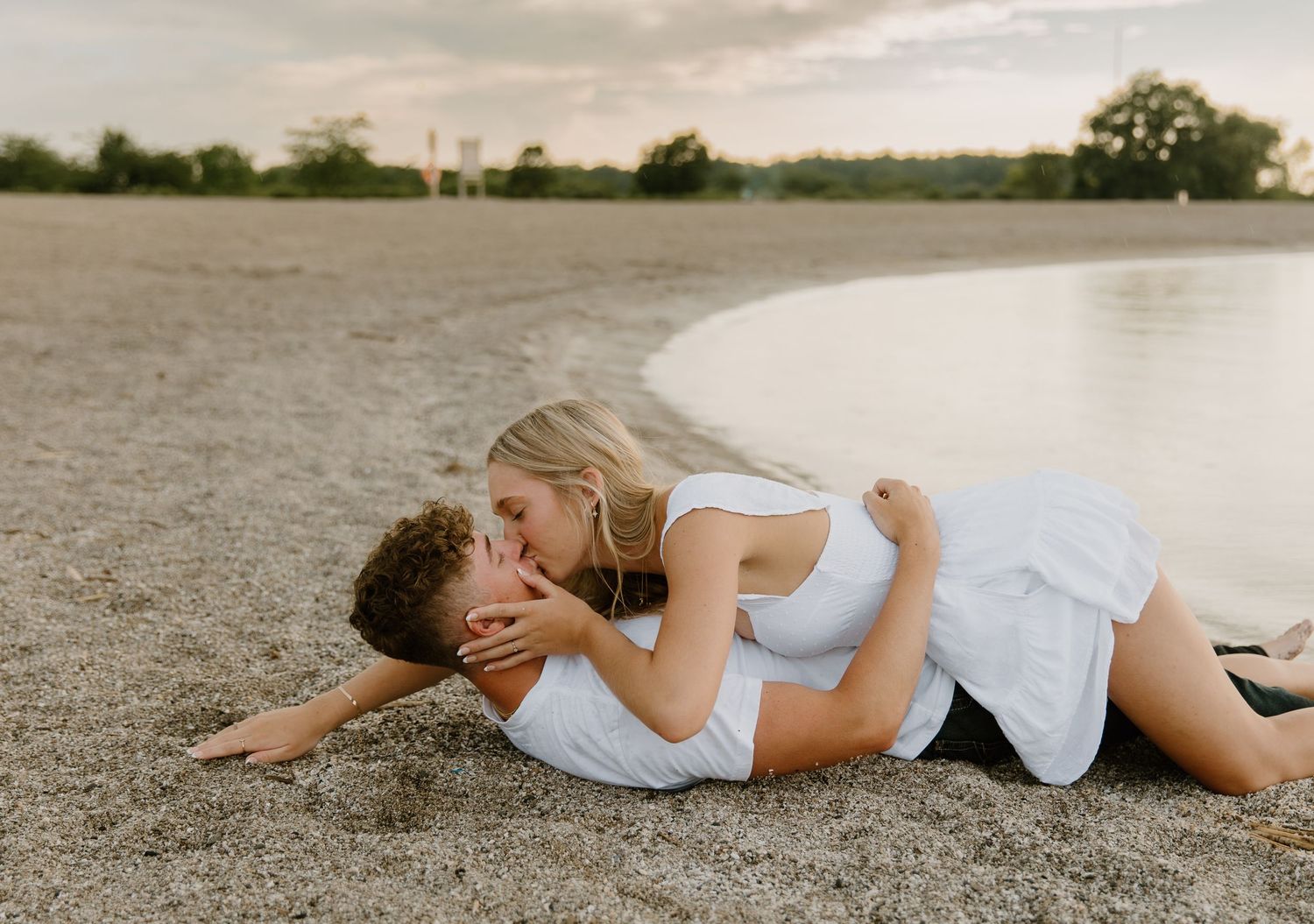 A series of artistic black and white photographs showing two people lying together on a beach at sunset.